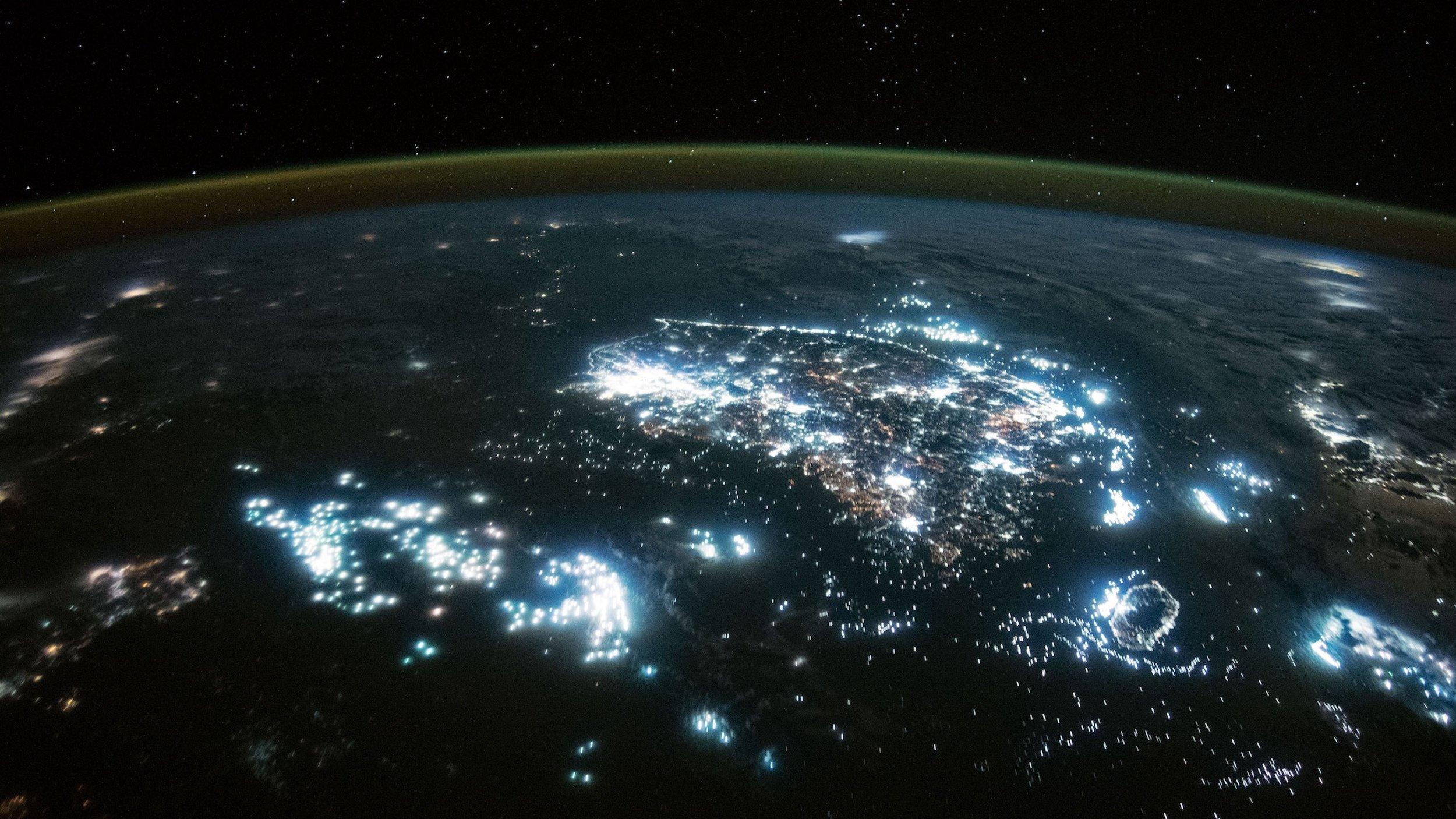 Night shot from space, you can see the curved globe and night cities shining brightly, as well as bright spots on the sea, the fishing fleets