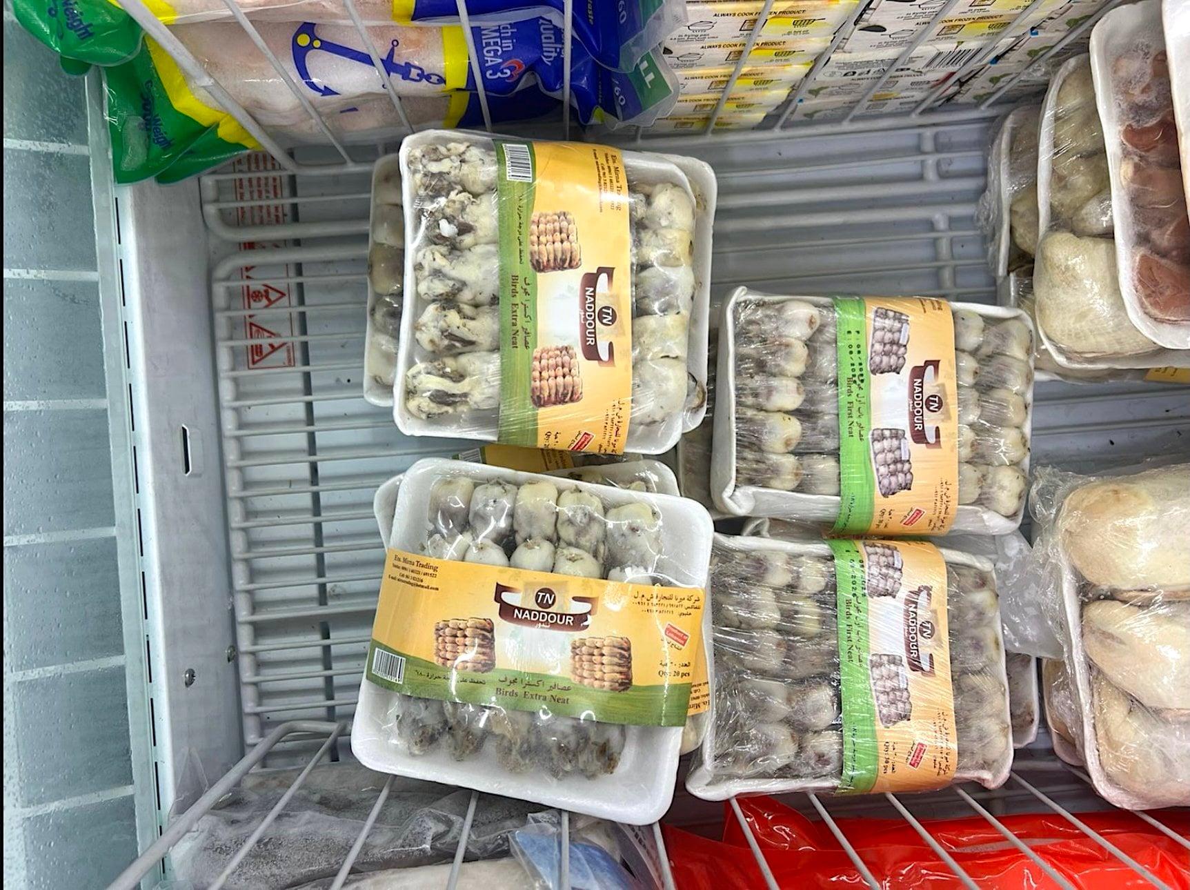 Eine Kühltruhe mit abgepackten Vögeln hinter Plastikfolie