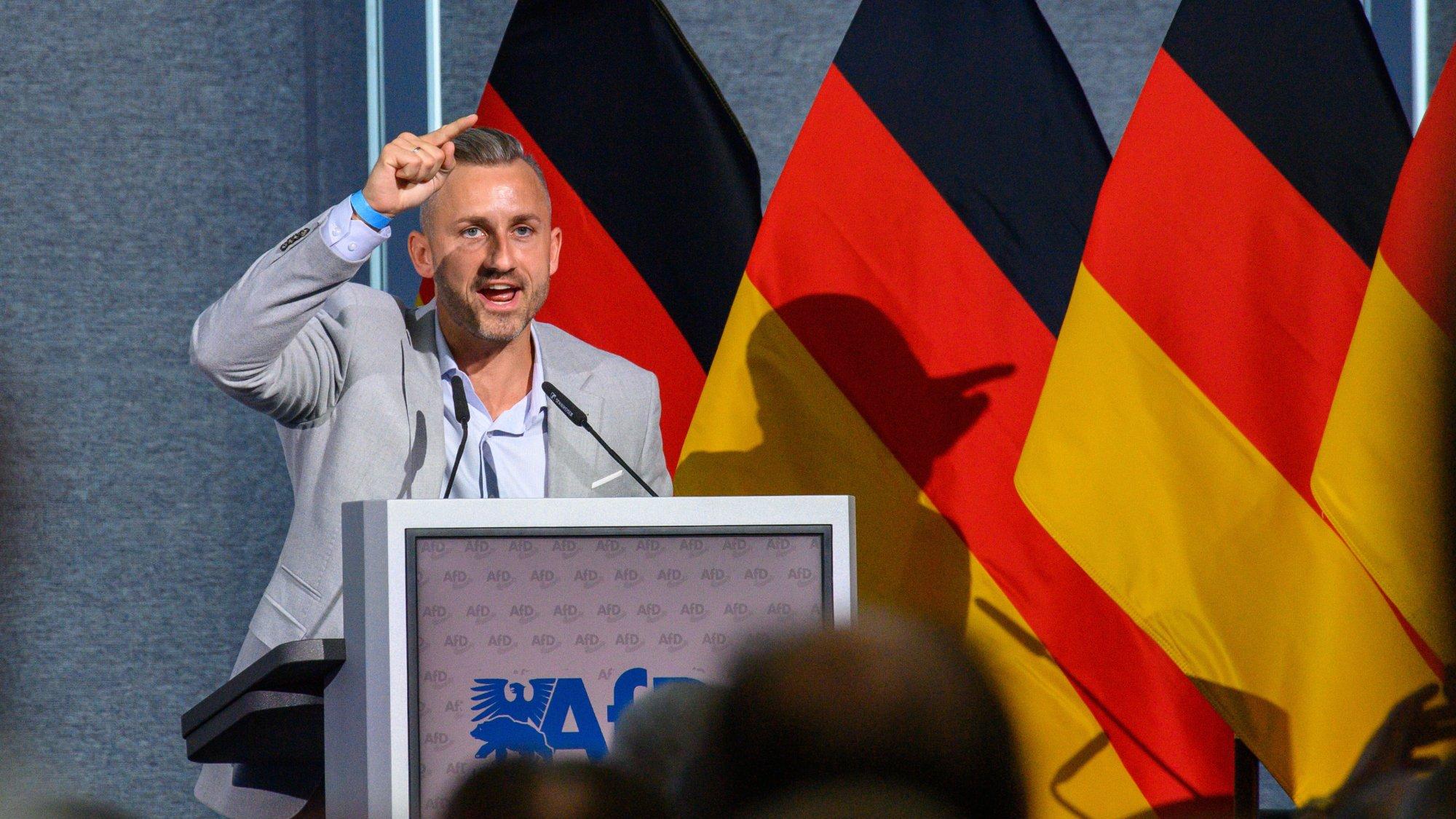 Vor mehreren Deutschlandflaggen steht der AfD-Politiker Ulrich Siegmund an einem Rednerpult. Beim SPrechen zeigt er mit dem ausgestreckten Zeigefinger über dem Kopf nach vorn in Richtung der Kamera.