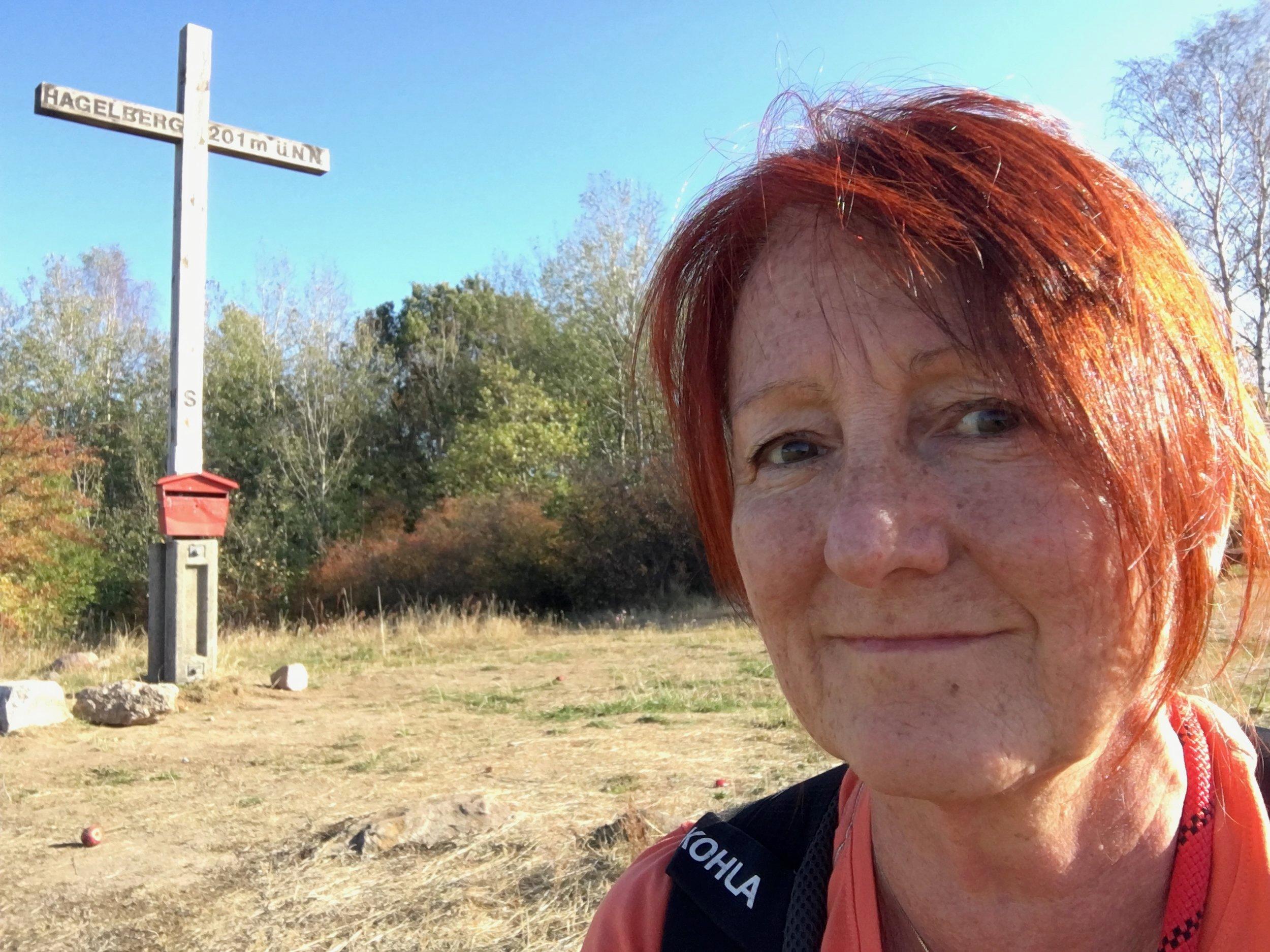 Eine Frau vor einem Gipfelkreuz.