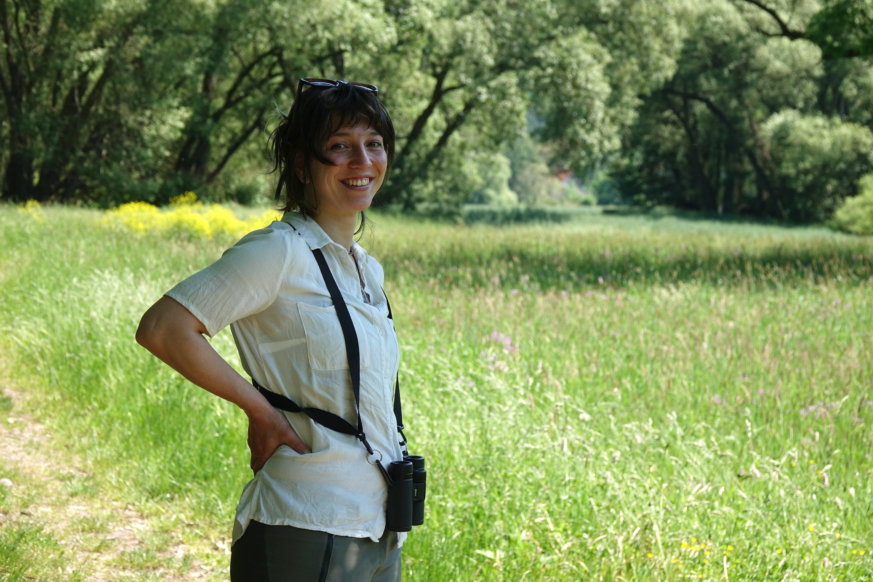Junge Frau mit Fernglas vor Feuchtwiese