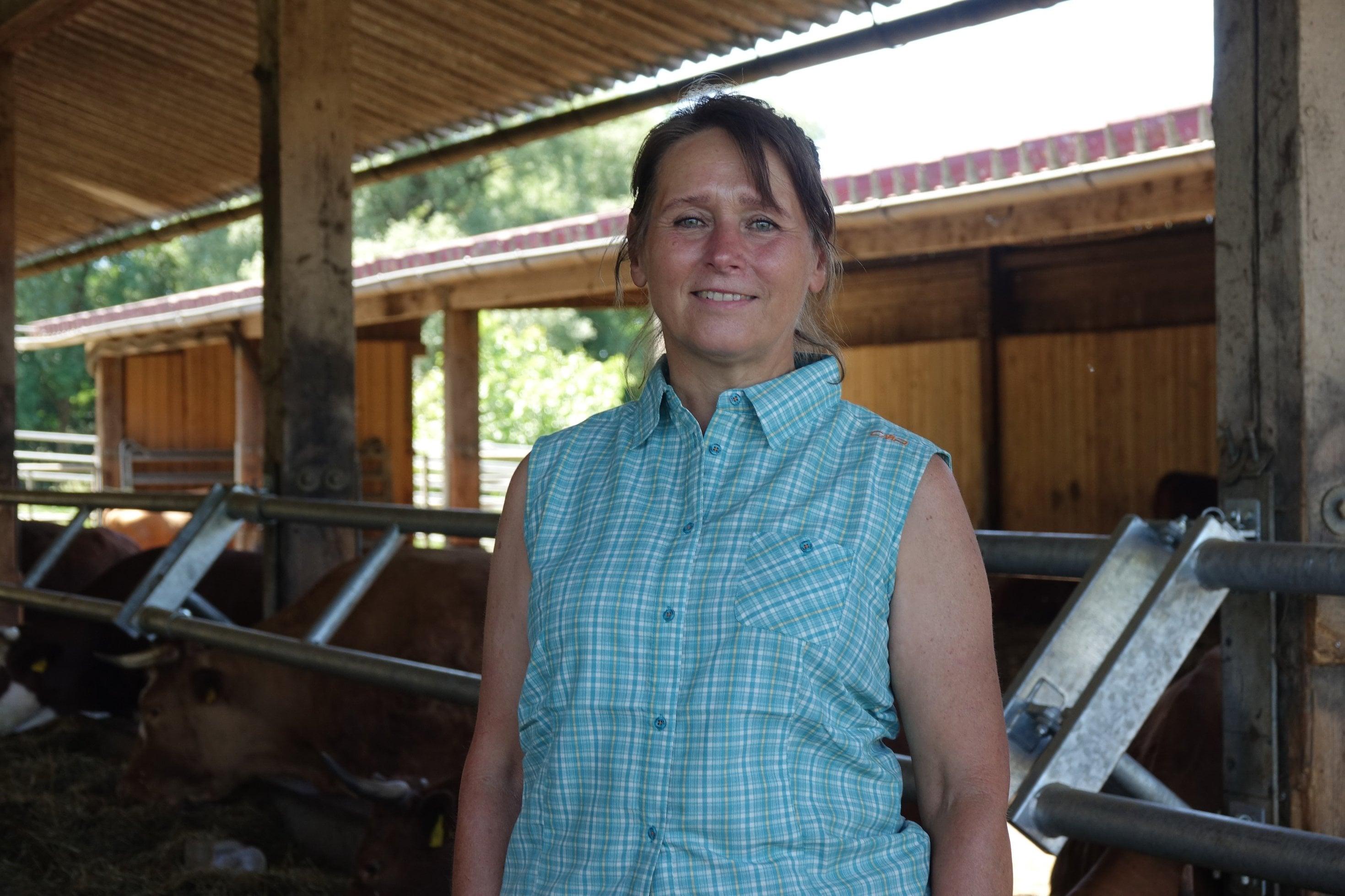 Frau mit festem Blick in offenem Rinderstall.