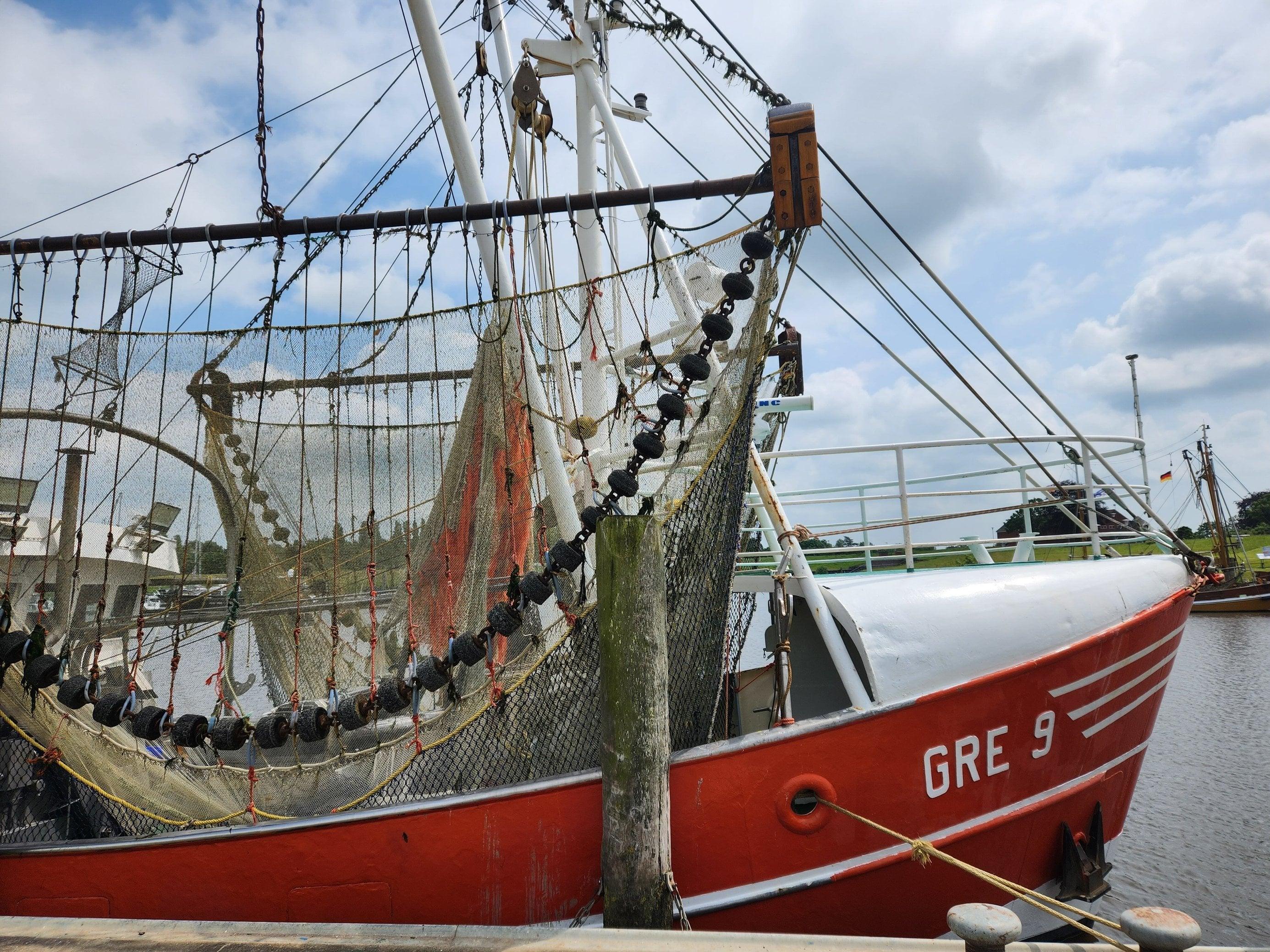 Foto zeigt einen Kutter im Hafen im ostfriesischen Greetsiel mit Dolly Ropes an seinen Netzen.