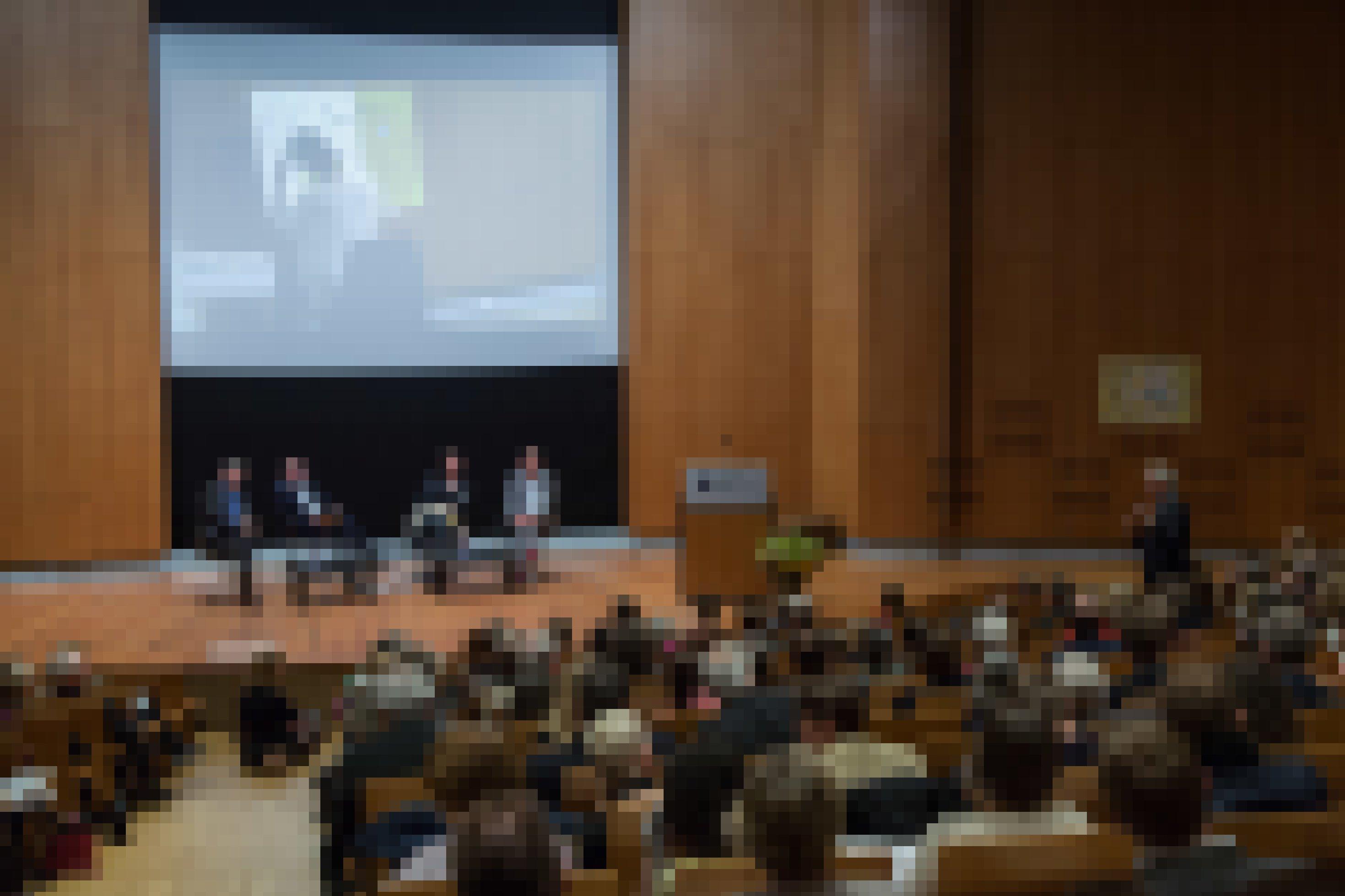 Das Foto zeigt einen großen Vortragssaal aus der Perspektive eines Zuschauers. Auf der Bühne sitzen hinter einem Tisch vier Personen.