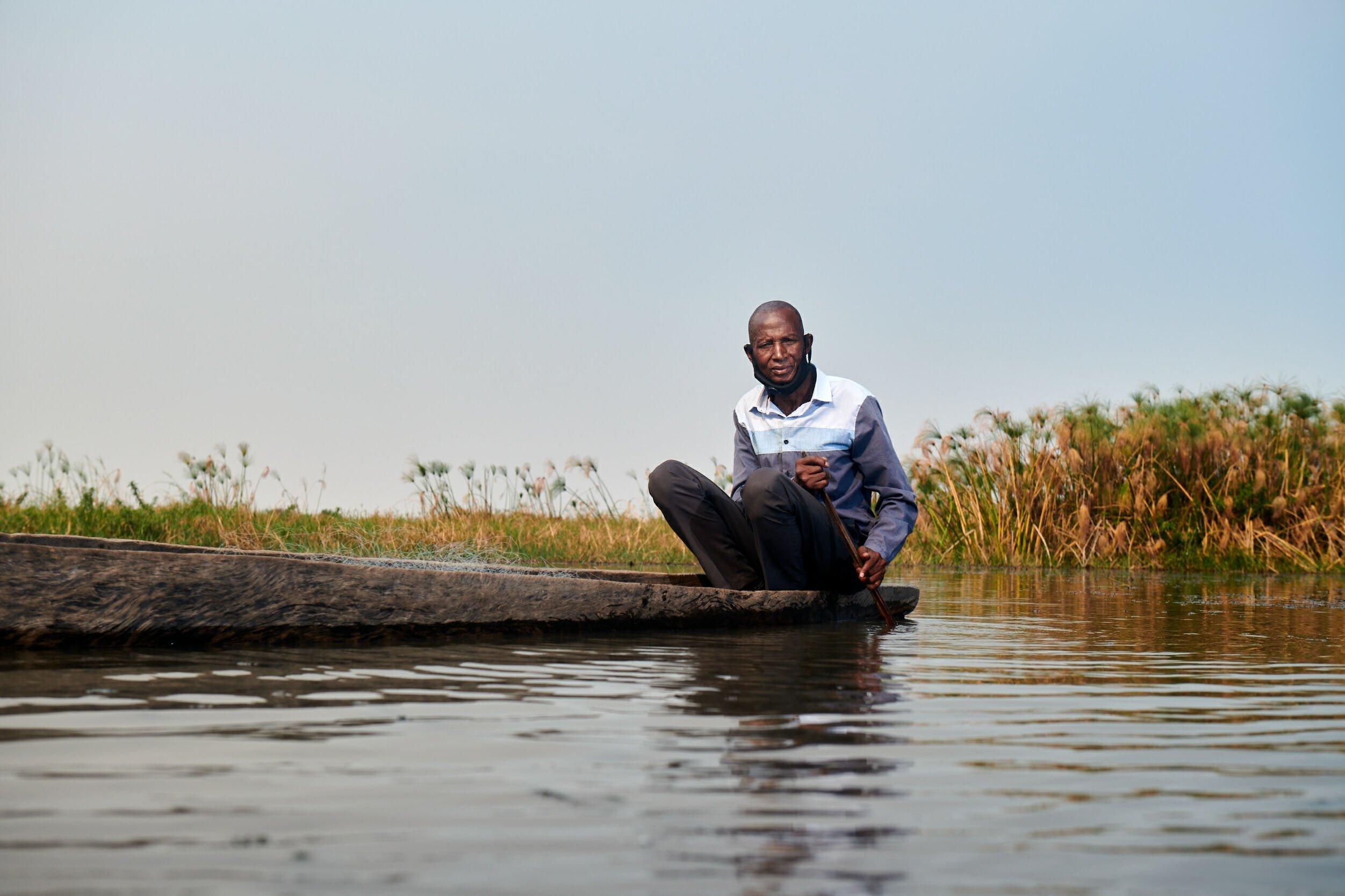 Der Fischer sitzt in seinem Makoro, dem traditionellen Einbaumboot der San