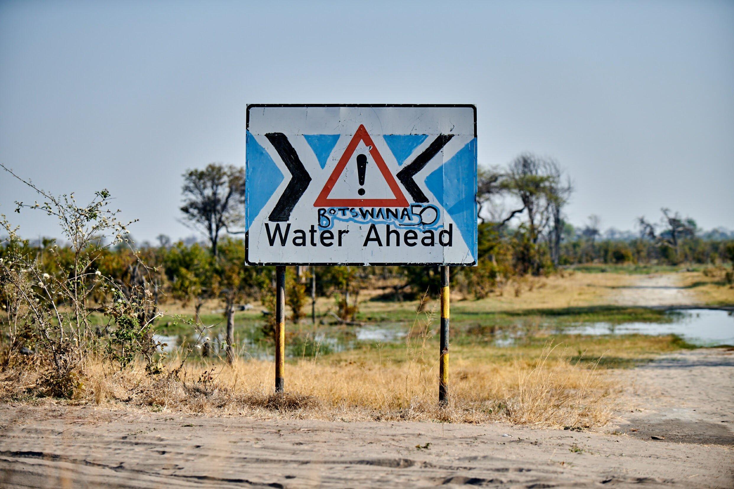 Auf dem Schild steht Botswana „Water Ahead“, es warnt vor möglichen Überschwemmungen