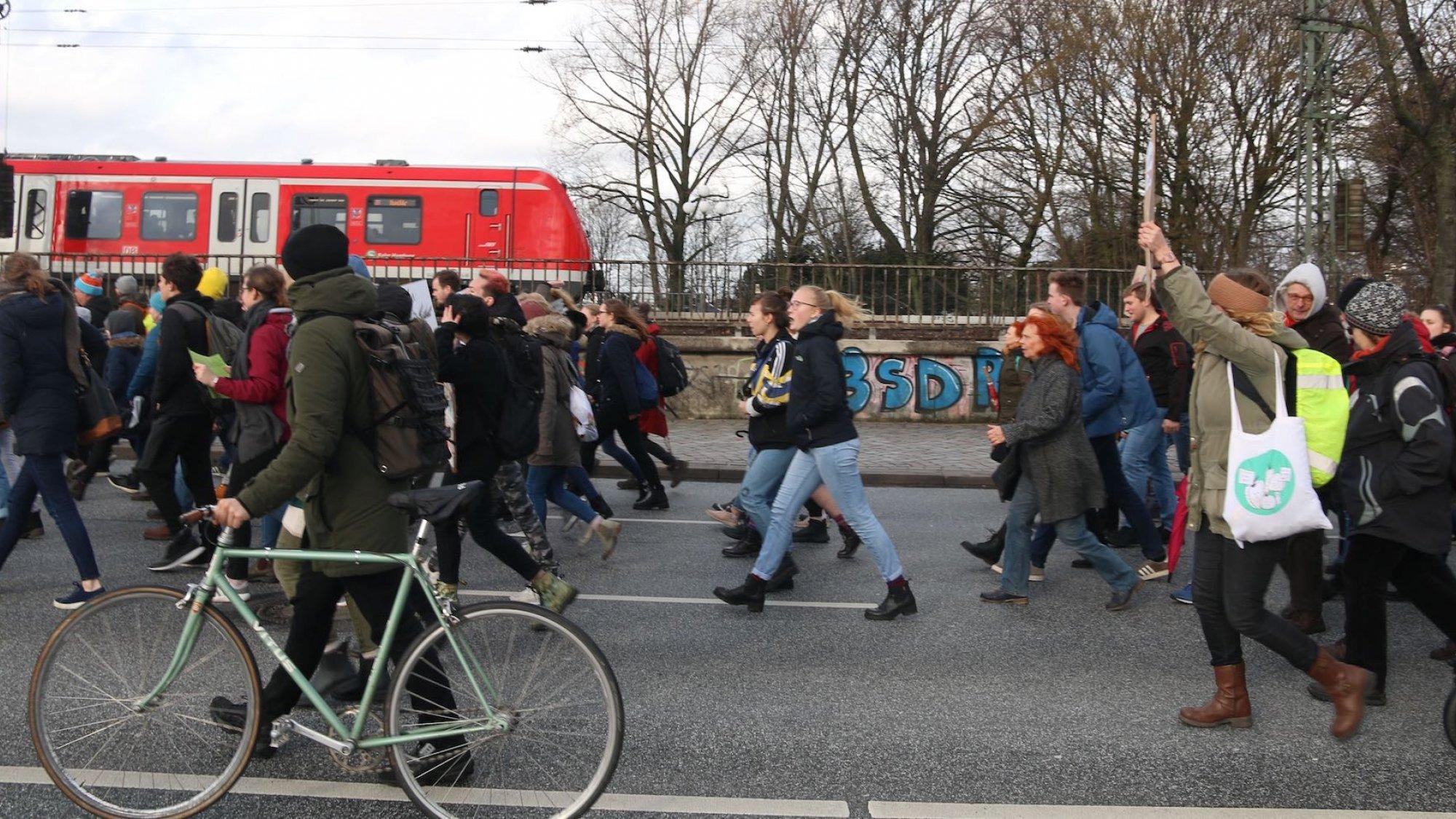Schüler gehen bei einem Schulstreik in Hamburg über die Lombardsbrücke; einer schiebt ein Fahrrad mit, im Hintergrund fährt die S-Bahn vorbei. Solche Demonstrationen markieren den Aufbruch in eine neue Zeit: Sie haben die Bundespolitik verändert und die Europawahl zu einer Abstimmung werden lassen, die stark von der Reaktion auf die Klimakrise geprägt war.
