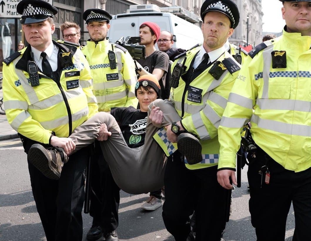Eine junger Demonstrant wird von mehreren Polizisten der Straße getragen