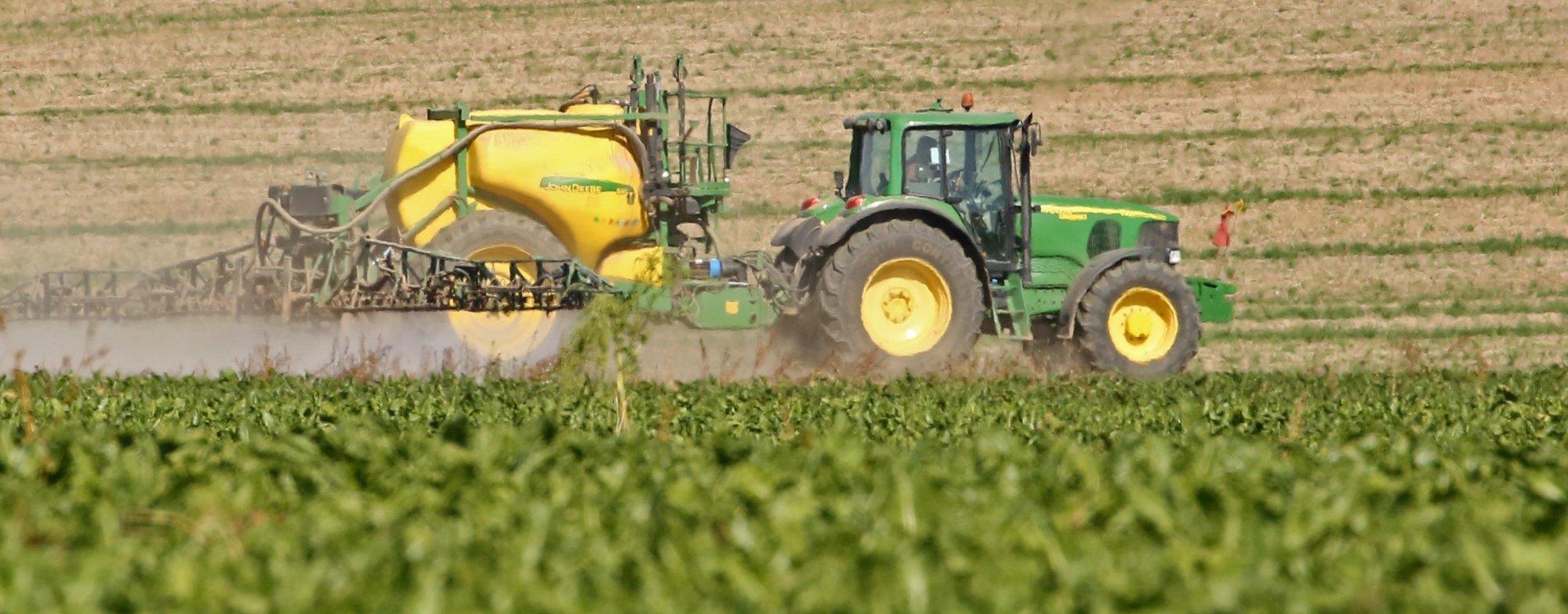 Ein Traktor spritzt Chemikalien auf einen Acker