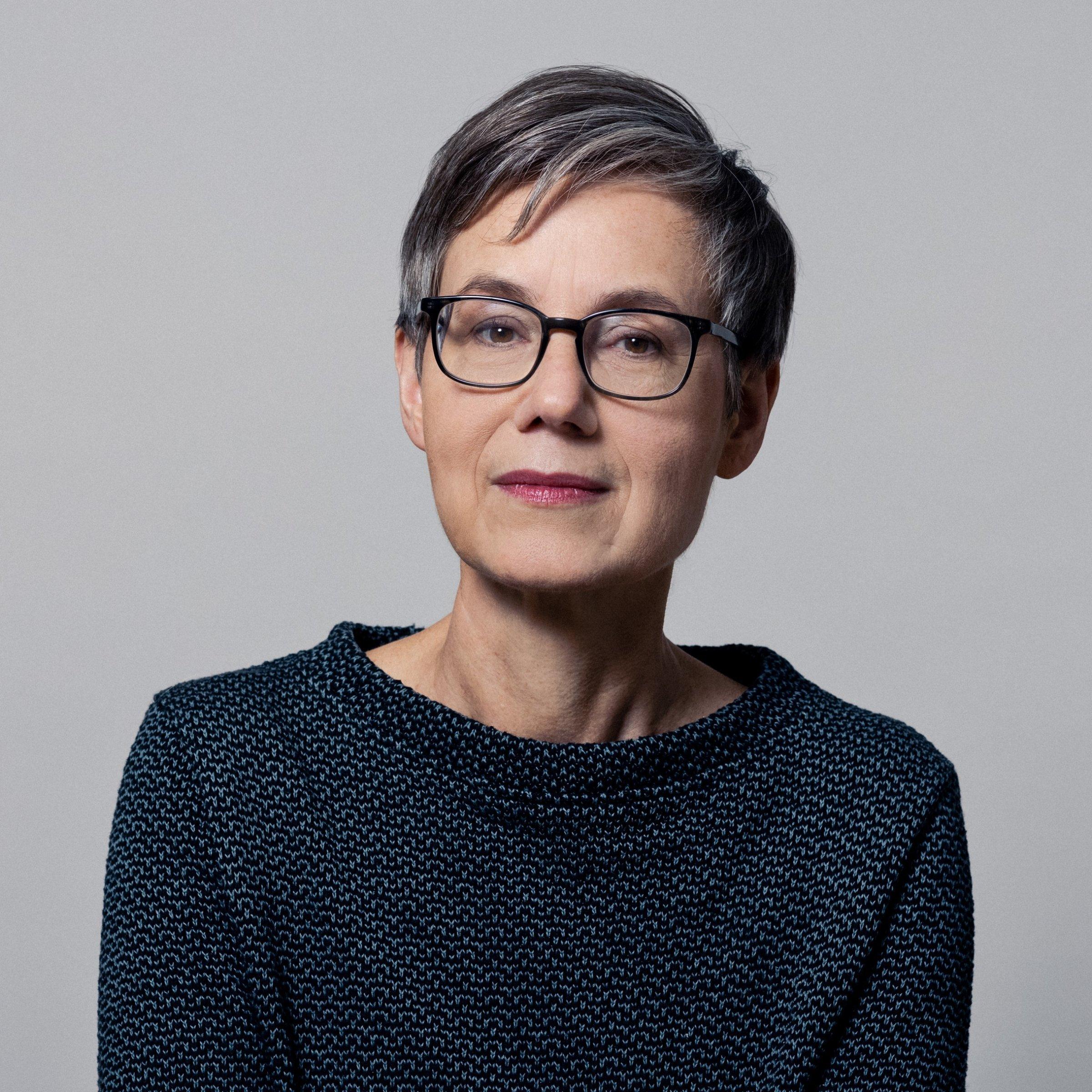 Lächelnde Frau mit kurzen, graumelierten Haaren.