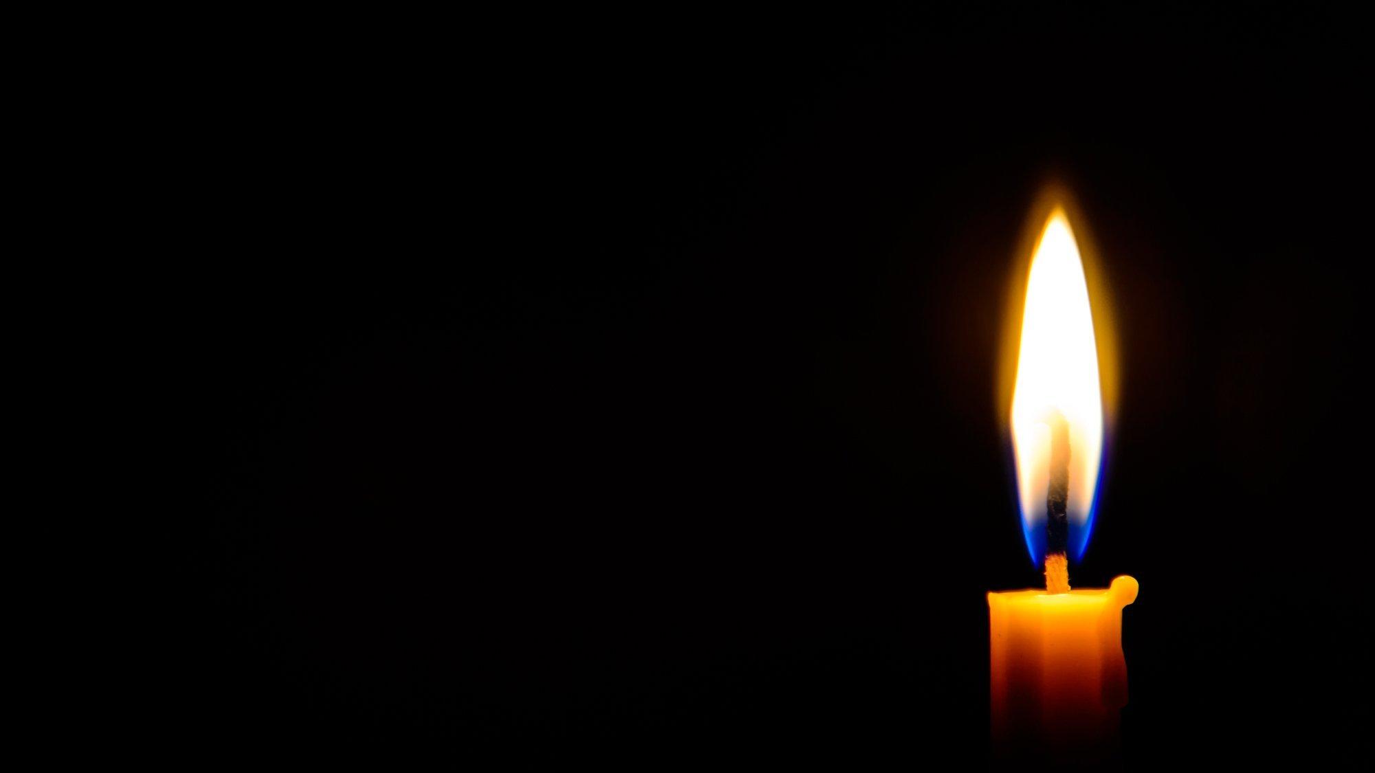 Eine brennende Kerze vor schwarzem Hintergrund