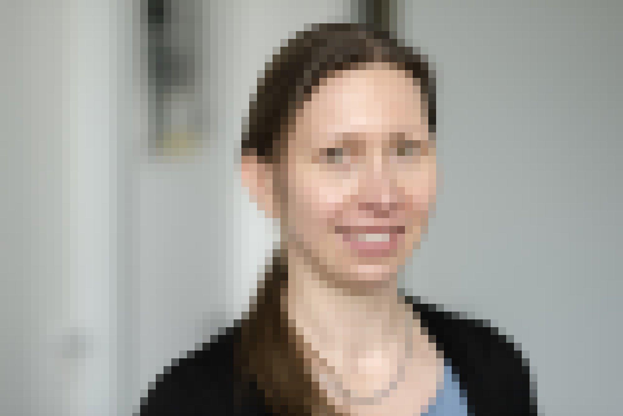 Alexandra Kirsch. Eine Portraitaufnahme einer lächelnden Frau mit längerem braunen Haar.