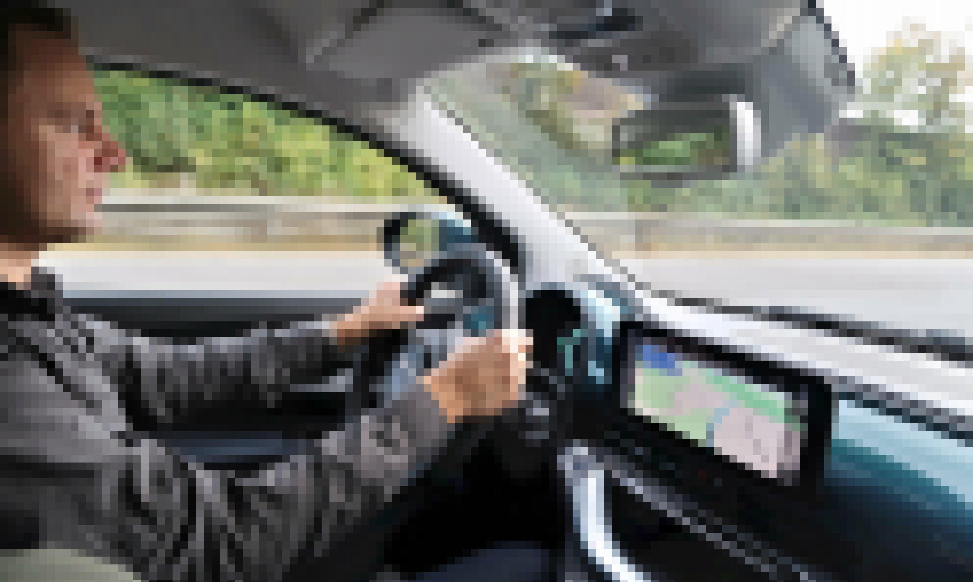 Ein Mann sitzt am Steuer eines Autos, das auf der Autobahn fährt. Blick in den Innenraum.