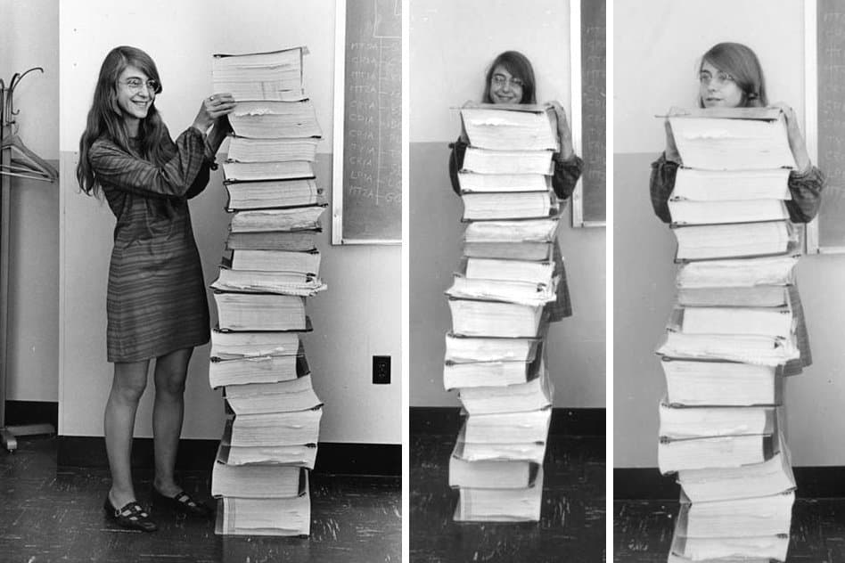 Eine Frau steht neben einem Stapel an Papierausdrucken, der ebenso hoch ist wie sie groß.