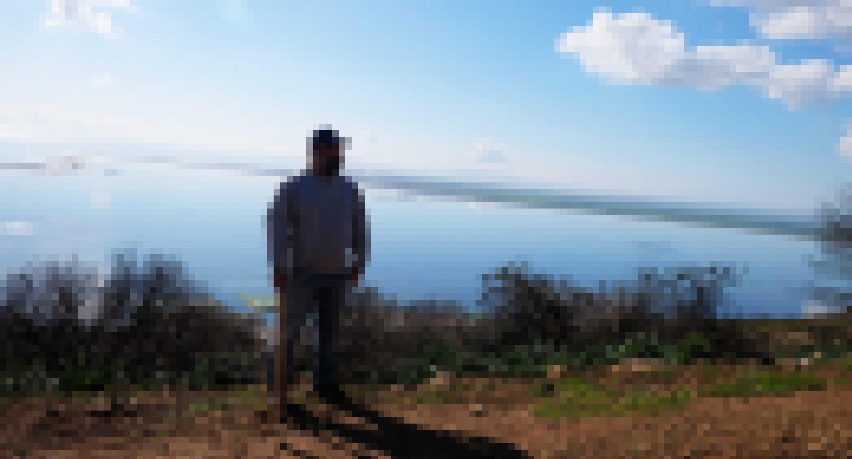 Ein Mann mit Bart und Käppi schaut in die Ferne, im Hintergrund ist das Meer zu sehen.