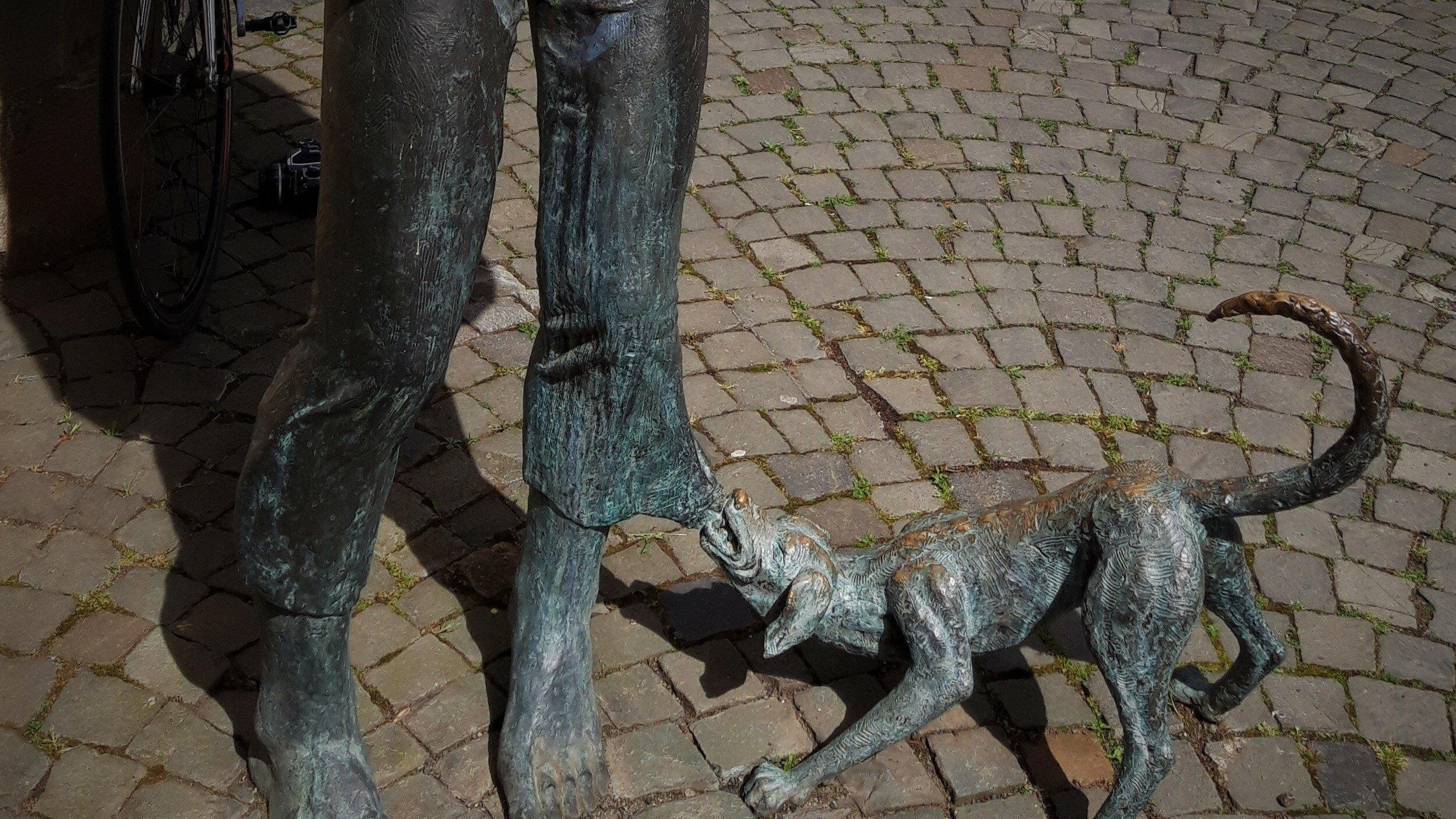 Im unteren Teil der Bad Kreuznacher Bronze-Plastik namens Dibbermann zerrt ein Hund am linken Hosensaum.