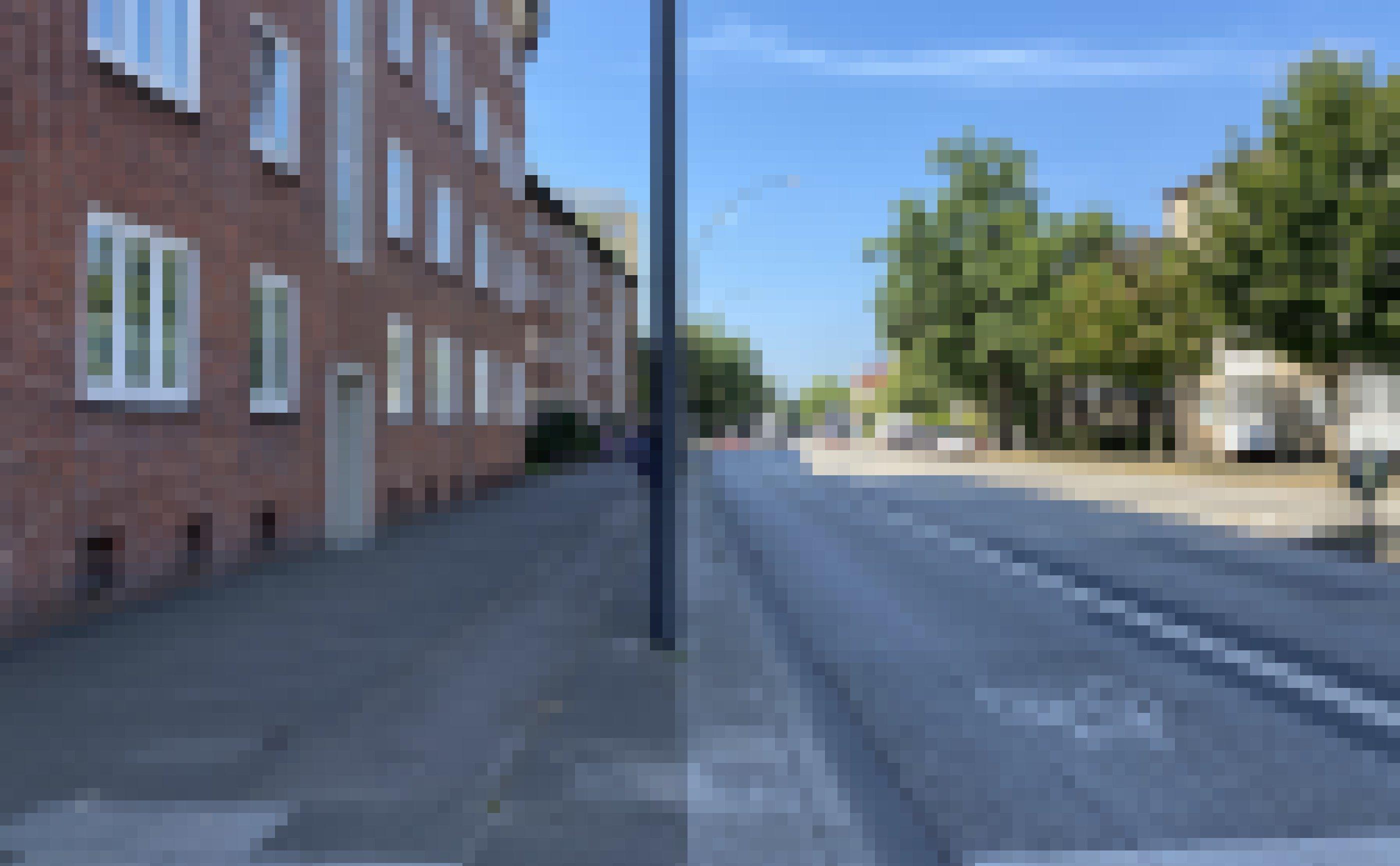 Vor dem Haus verläuft ein breiter Gehweg und eine Straße.