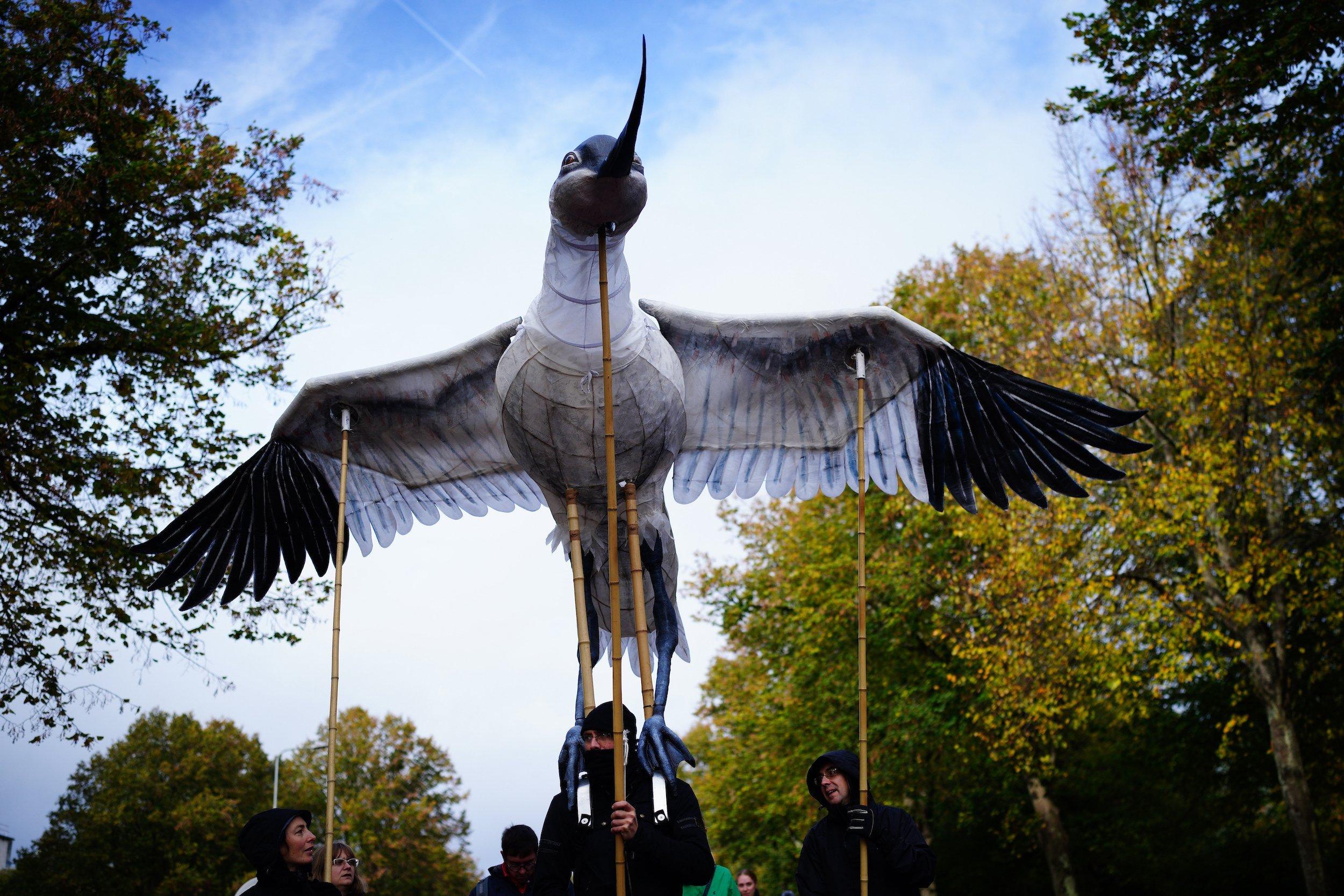 Demonstranten tragen einen großen Vogel aus Papier