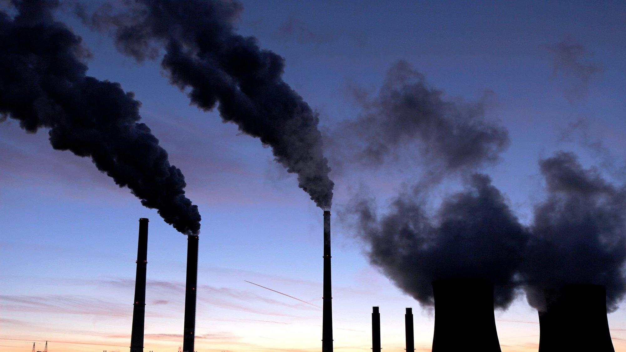 Totale mit Abenddämmerung: Ein Kohlekraftwerk stößt schwarze, klimaschädliche Emissionen aus.