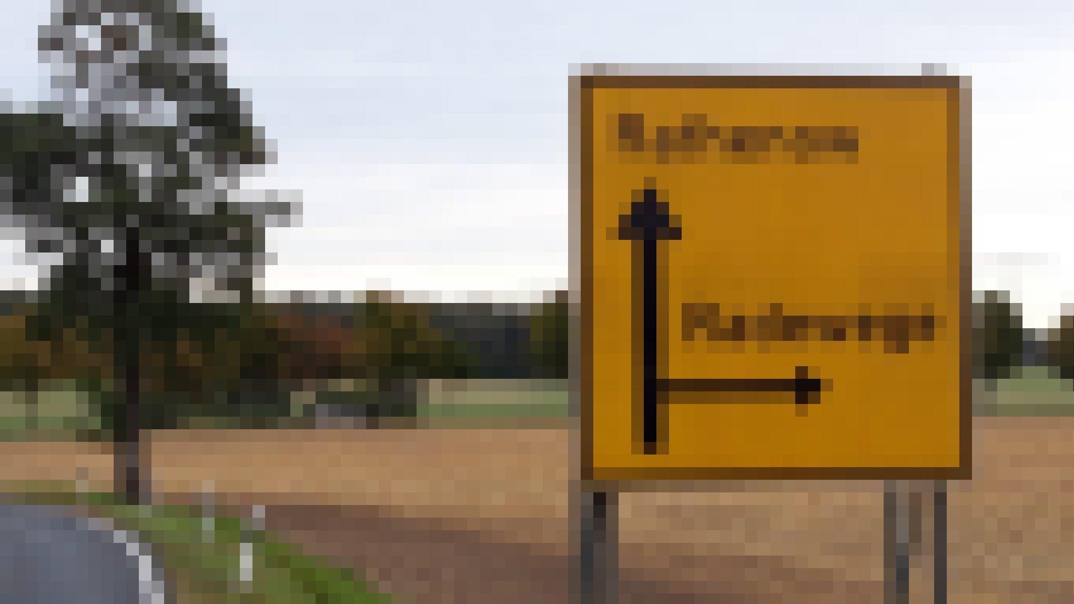 Vor einem Straßenschild, das an der nächsten Kreuzung rechts das Ort namens Radewege ausweist.