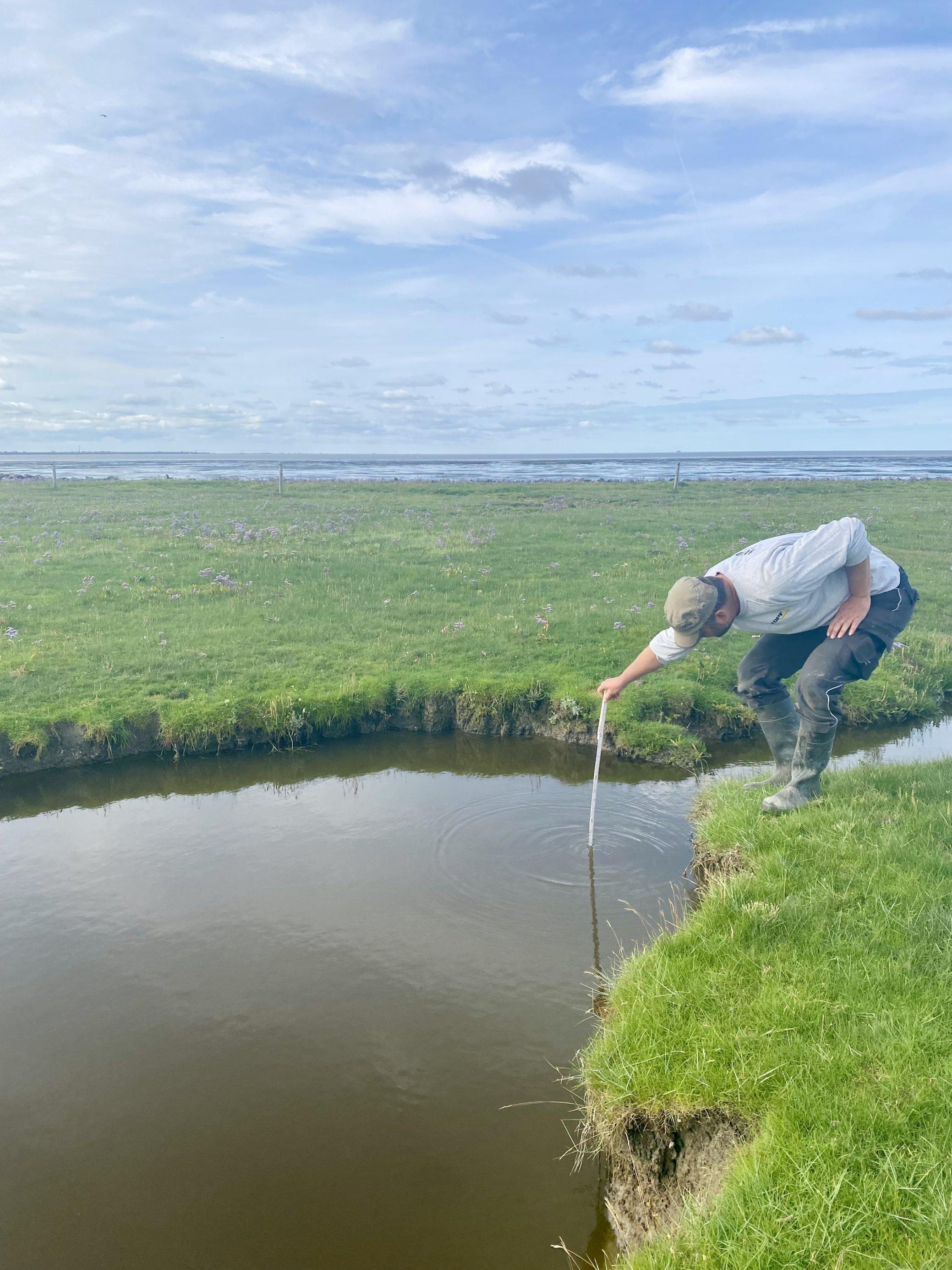 Mann hält einen Zollstock in einen Graben