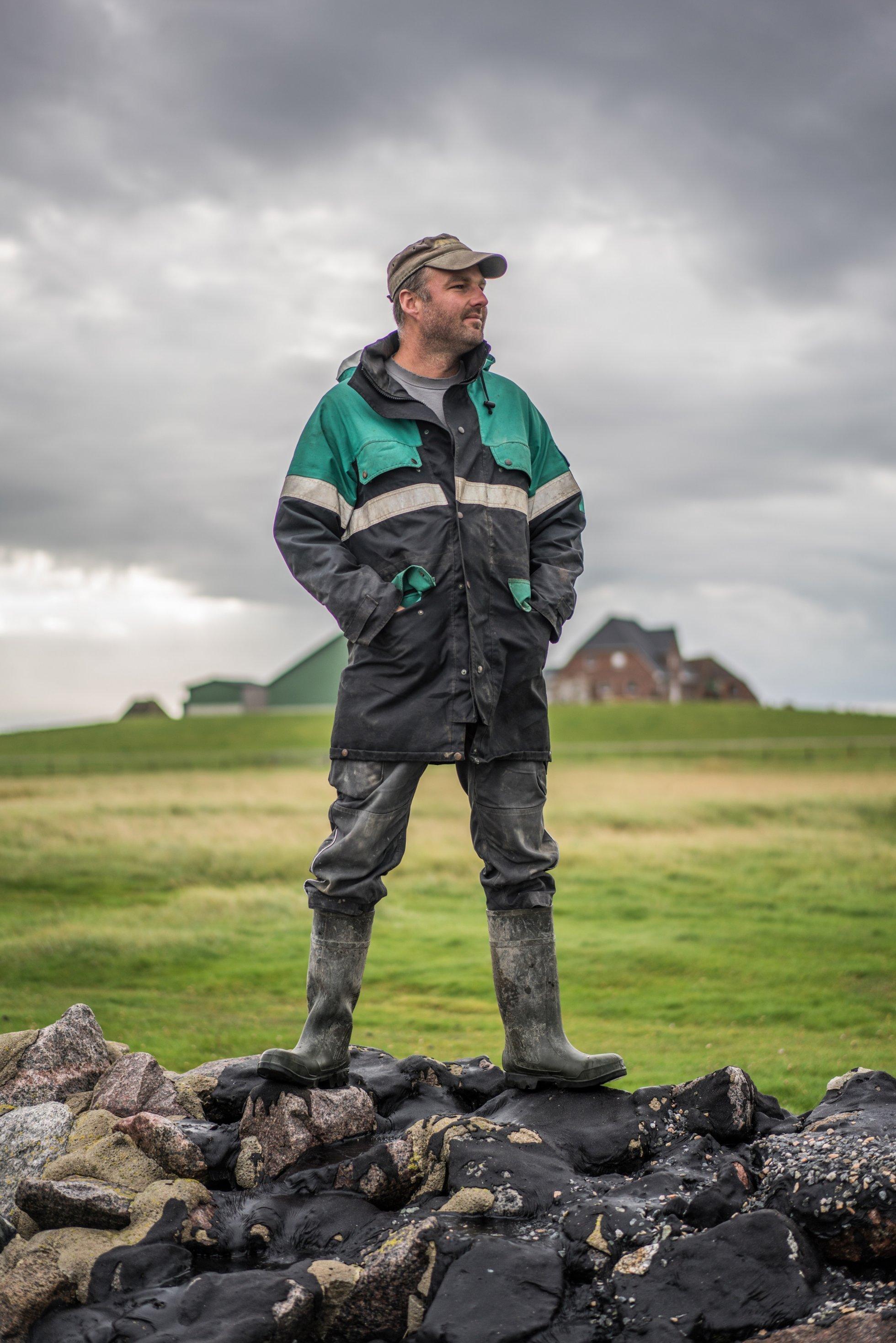 Mann steht auf Steindamm und schaut in die Ferne