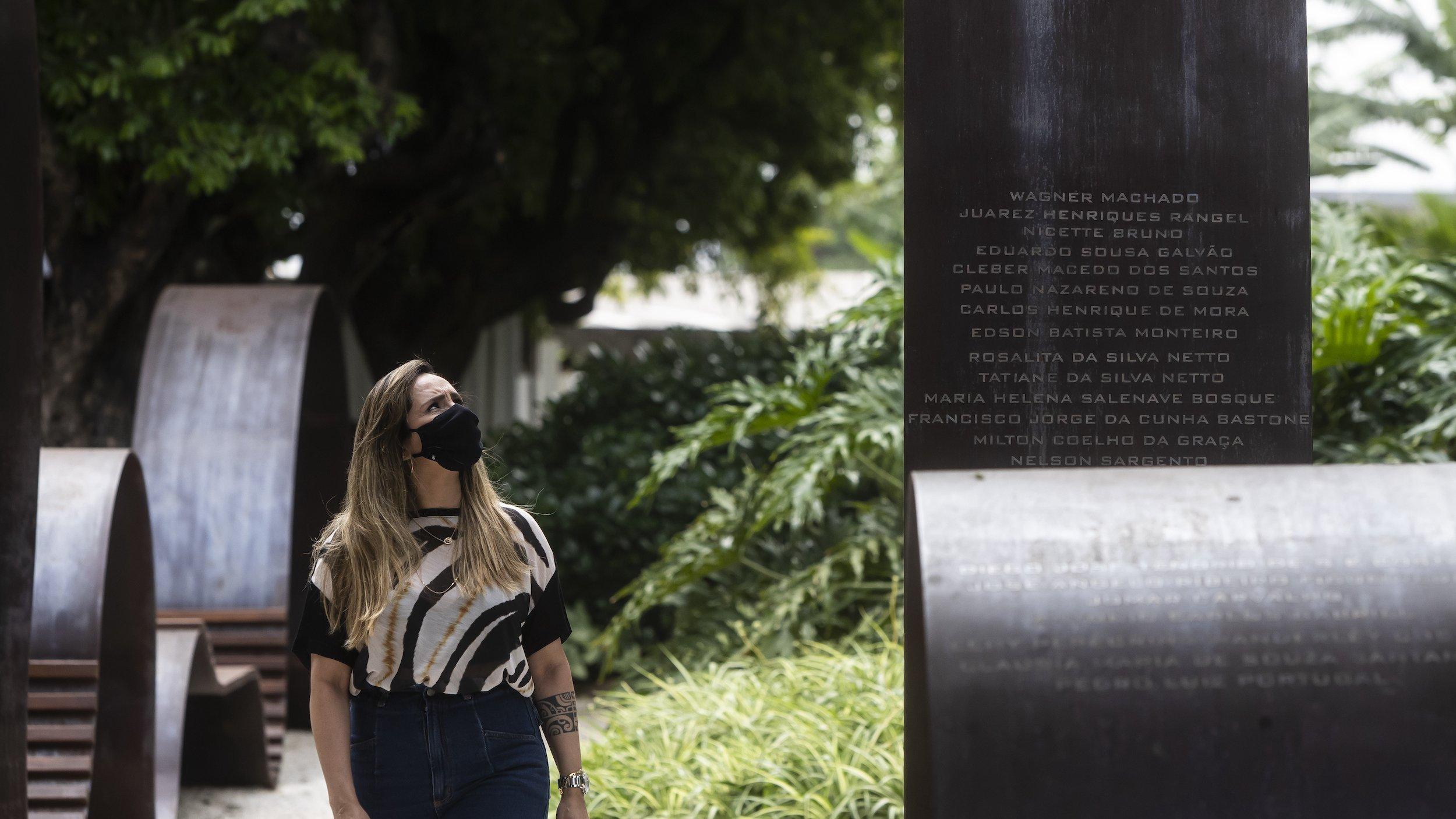Eine Frau steht neben der Corona-Gedenkstätte – lange metallische Banden mit den Namen von Verstorbenen.
