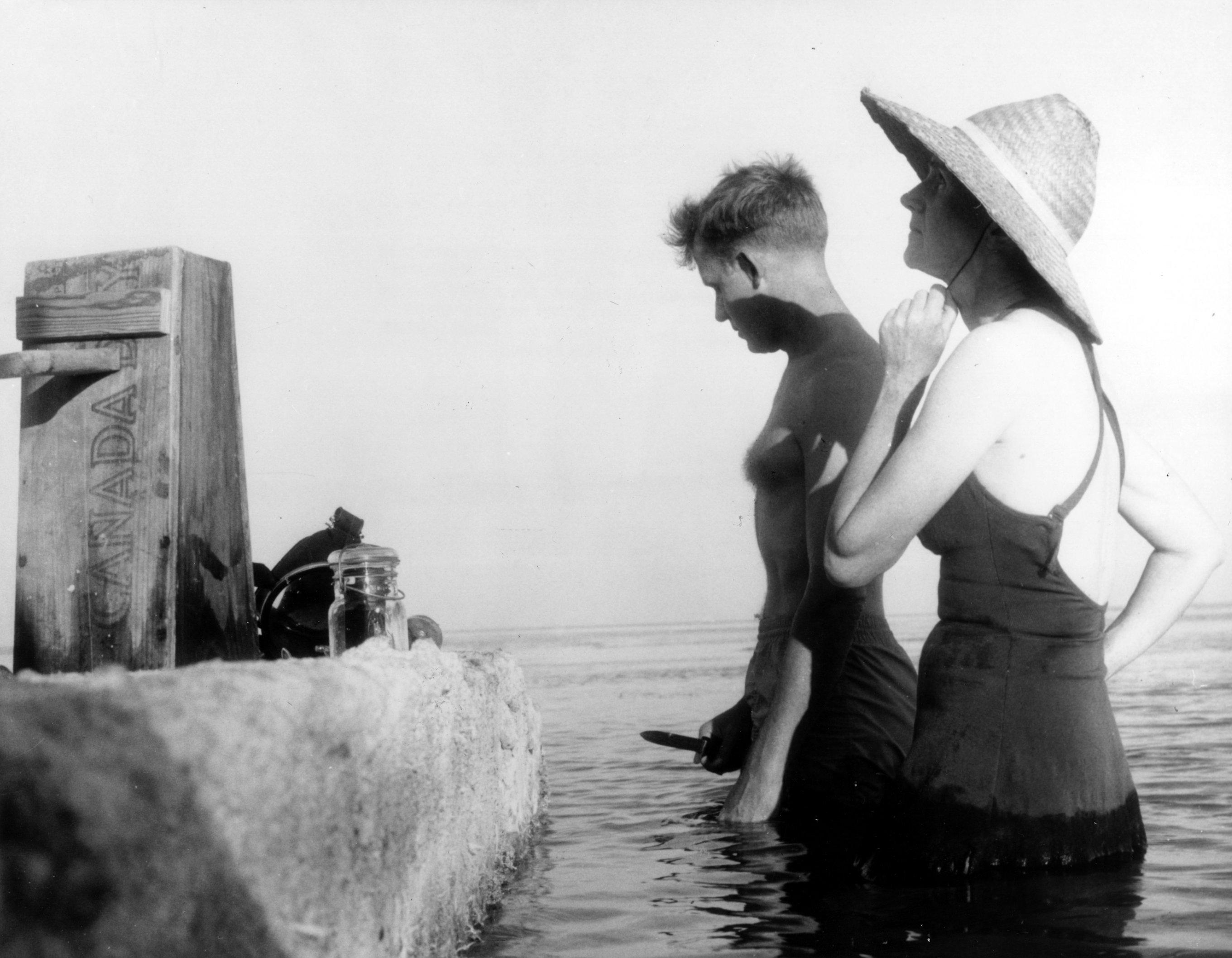 Eine Frau und ein Mann stehen in Badekleidung im Meerwasser.