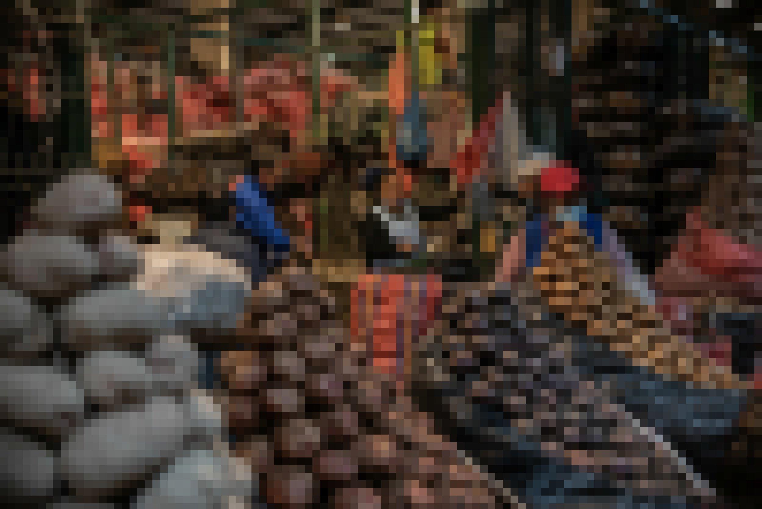 Eine Markthalle des Nachts, schummriges Licht. Im Vordergrund nach Sorten aufgestapelte Kartoffeln, dahinter Marktfrauen und noch meterhohe Stapel mit gefüllten Kartoffelsäcken.