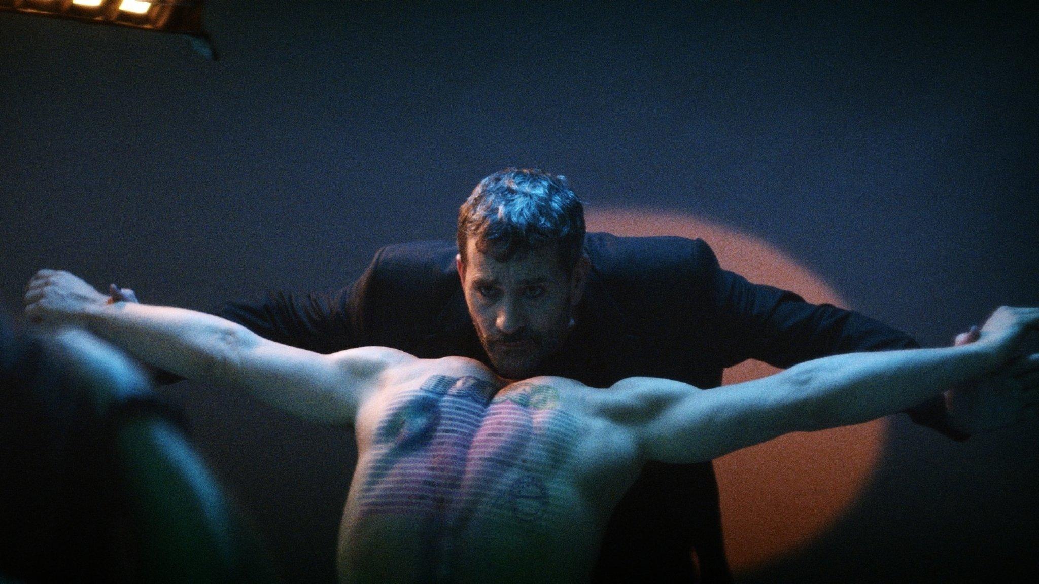 Filmstill aus "The Man Who Sold His Skin". Der Künstler schaut über den tätowierten Rücken seines Kunstwerks in die Kamera