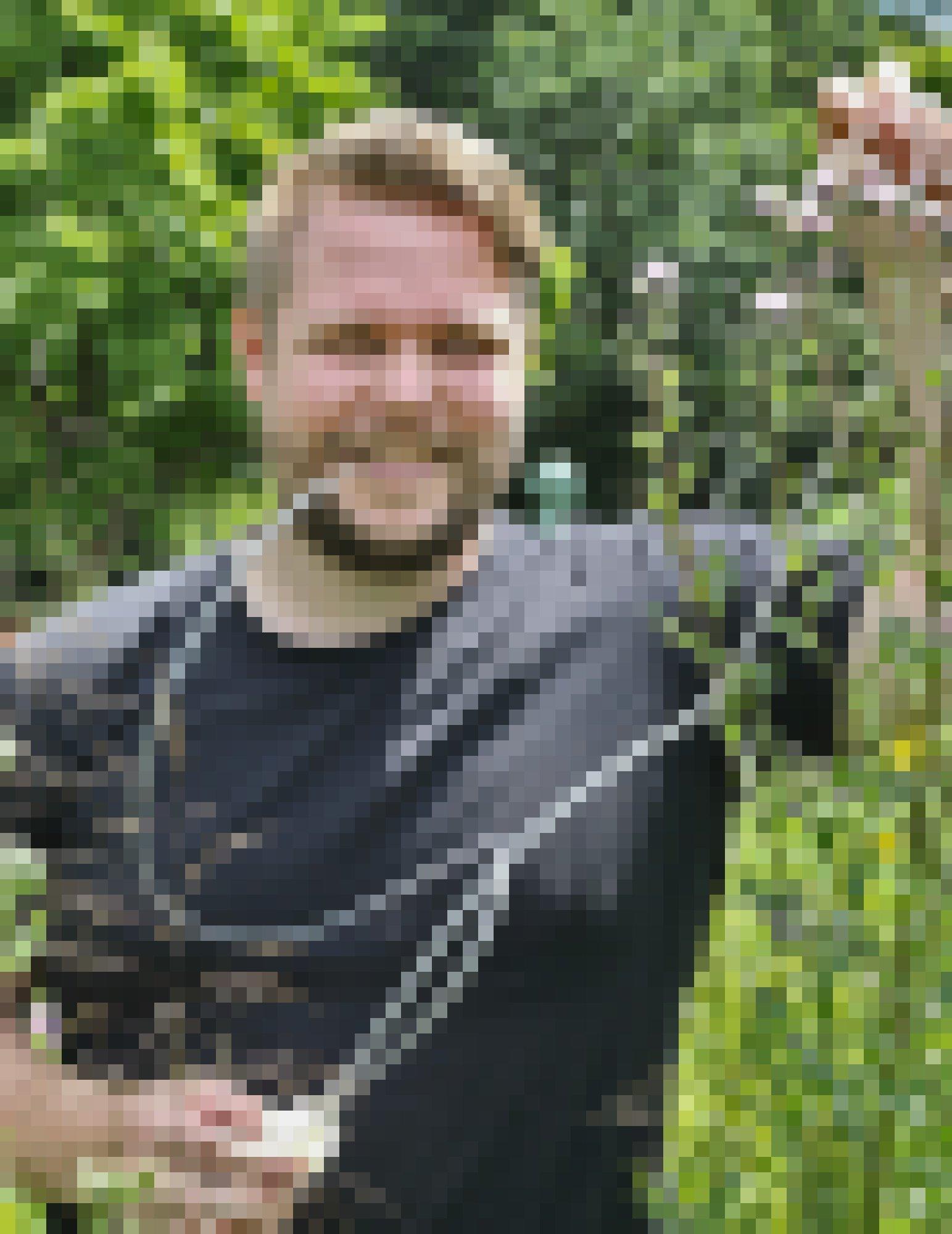 Käferforscher Thomas Hörren steht neben mannshohen Disteln und saugt mit einer Insekten-Sammelapparatur Insekten ein