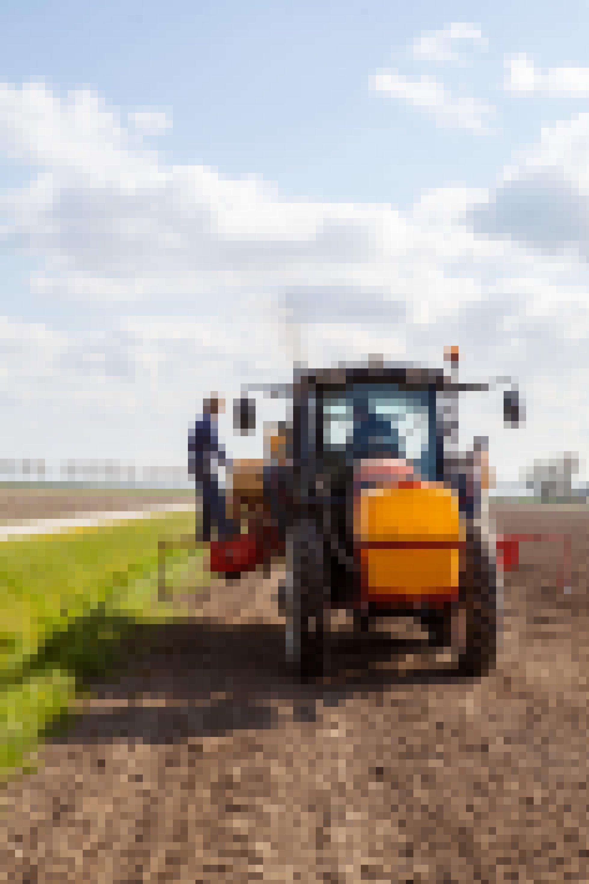 Zwei Bauern bearbeiten mit einem Traktor einen Acker.