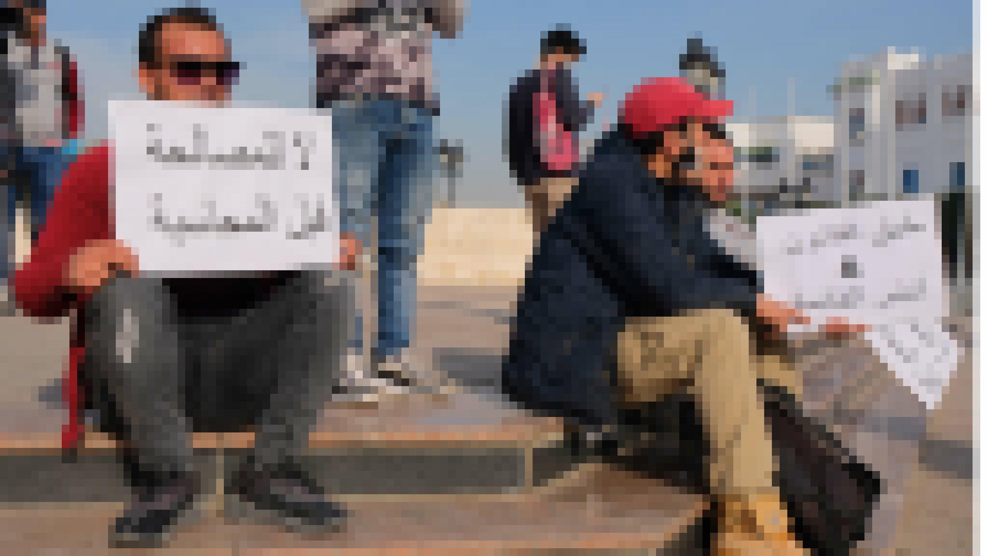 Junger Mann sitzt auf Treppe vor dem Regierungssitz in Tunis. In der Hand hält er ein Plakat mit dem Slogan „Keine Versöhnung ohne vorherige Rechenschaft“