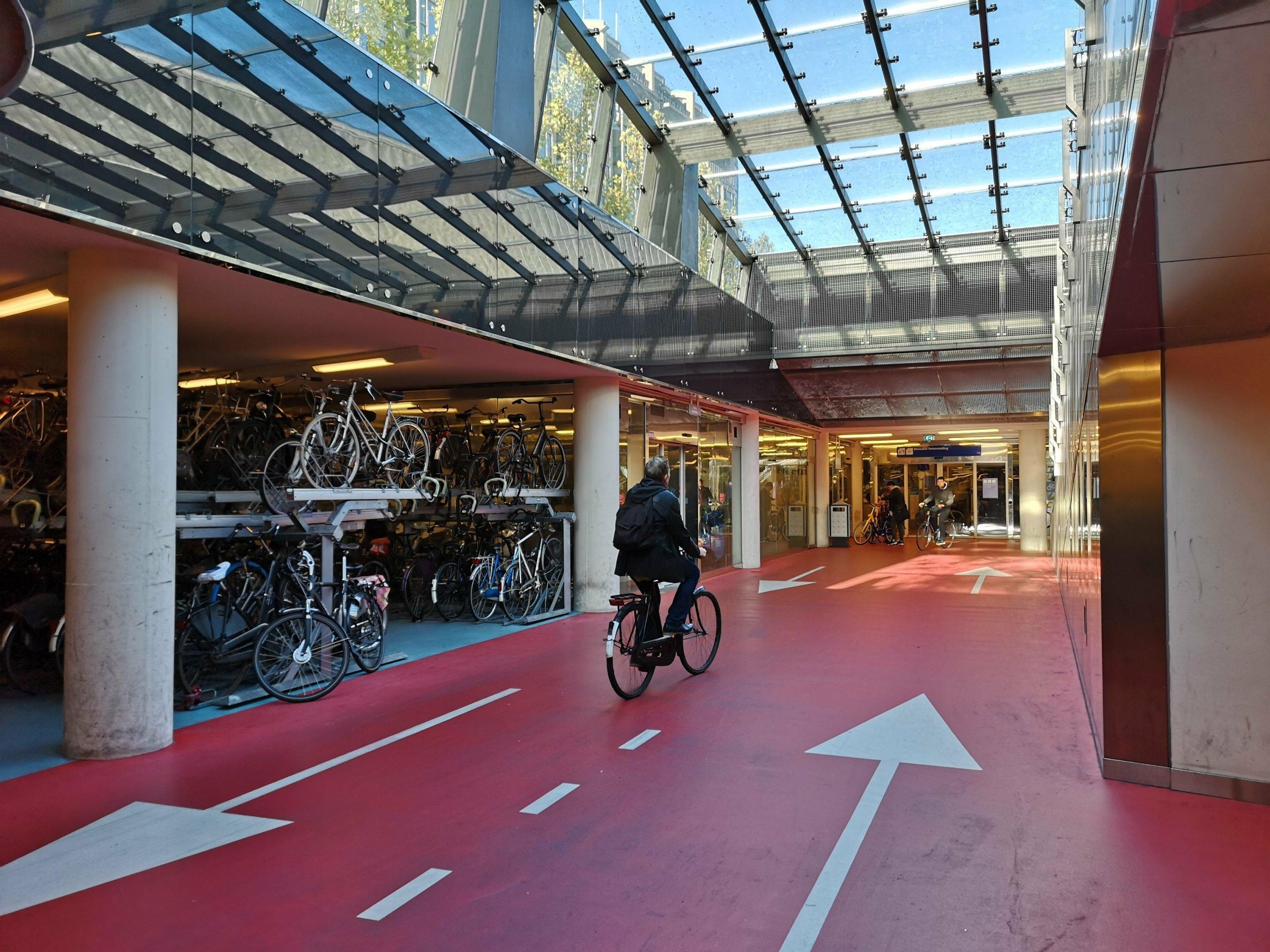 In Doppelstockgaragen sind die Fahrradräder in dem Parkhaus abgestellt. Ein Radfahrer fährt Richtung Ausgang