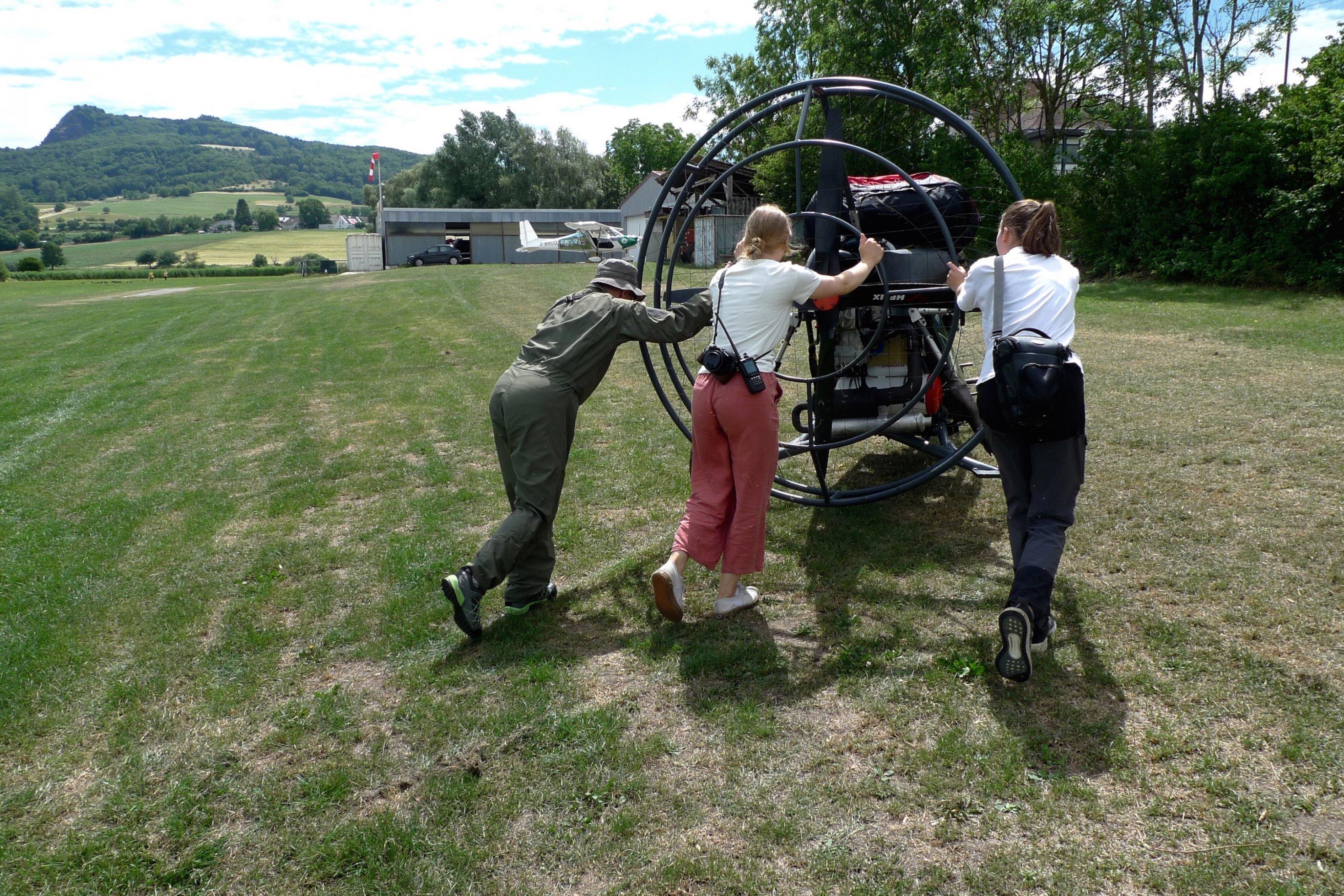 Walter Holzmüller, Laura Pahnke und Gine Gerecke stossen das Fluggerät zurück in den Hangar des Flugplatzes Binningen.