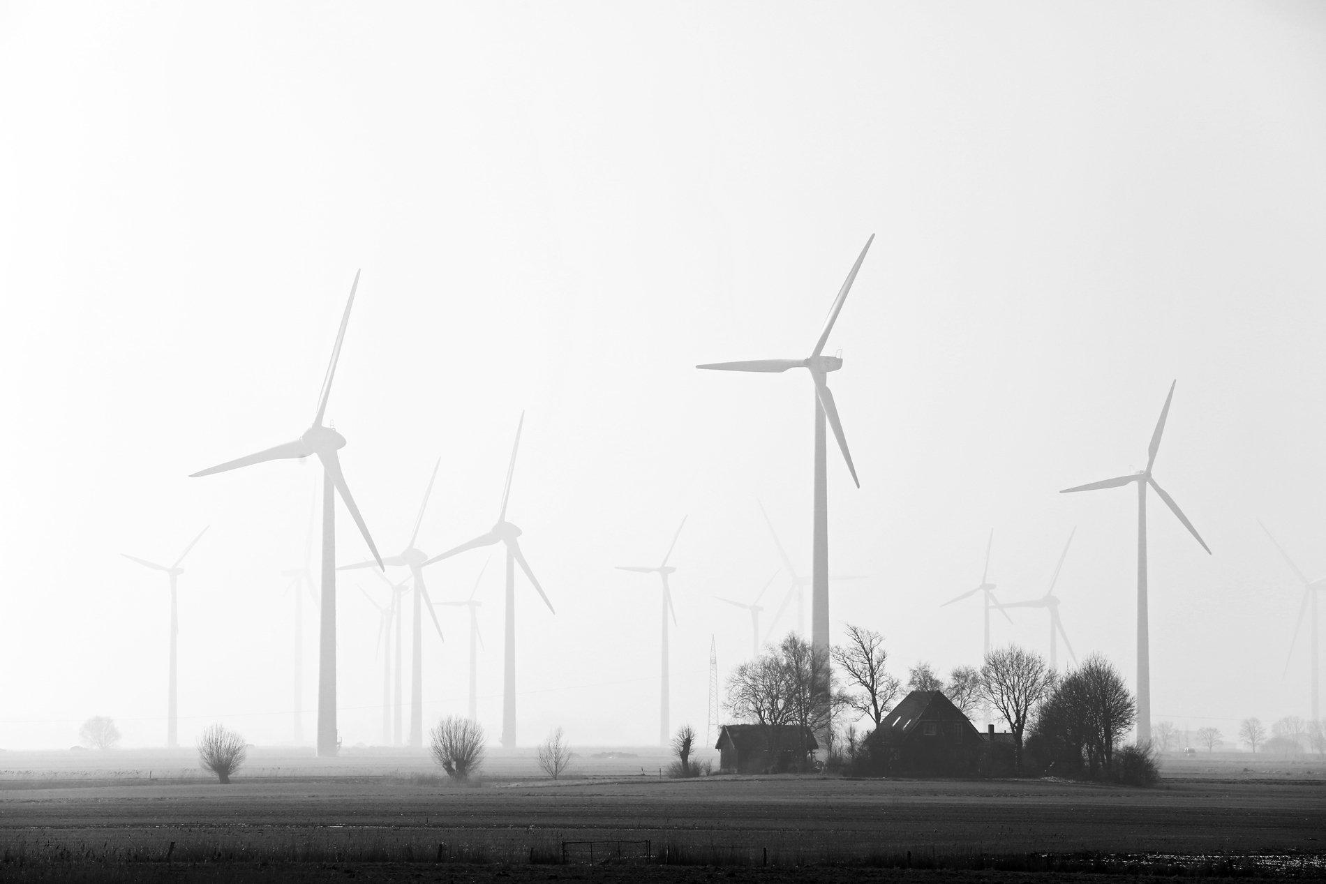 Ein schwarz-weiß-Foto von Windrädern und einem Gehöft.