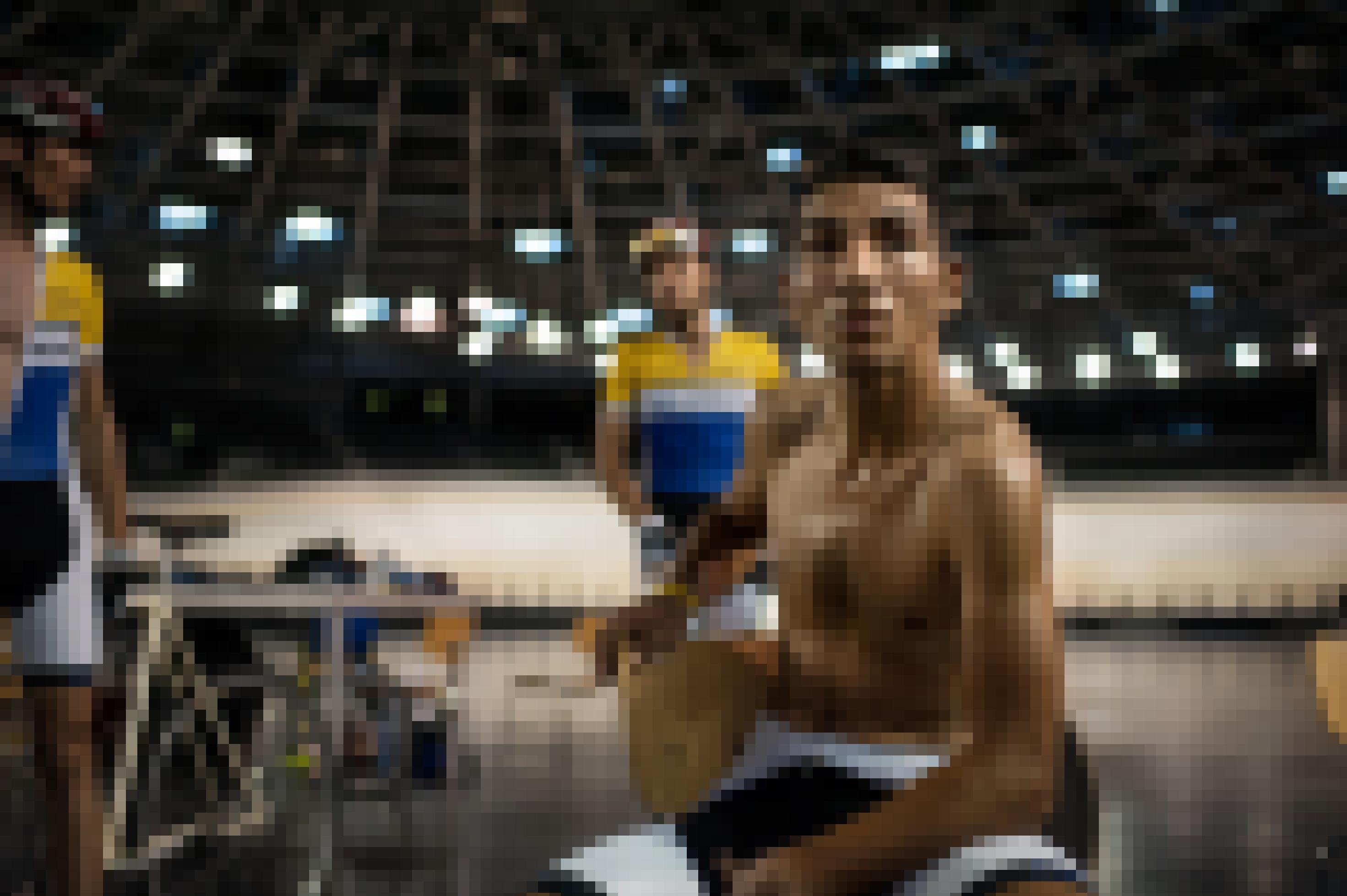 Tarek Al-Moakee sitzt in Radlerhosen auf einem Stuhl im Berliner Velodrom und ruht sich aus. Im Hintergrund zwei weitere Radfahrer.