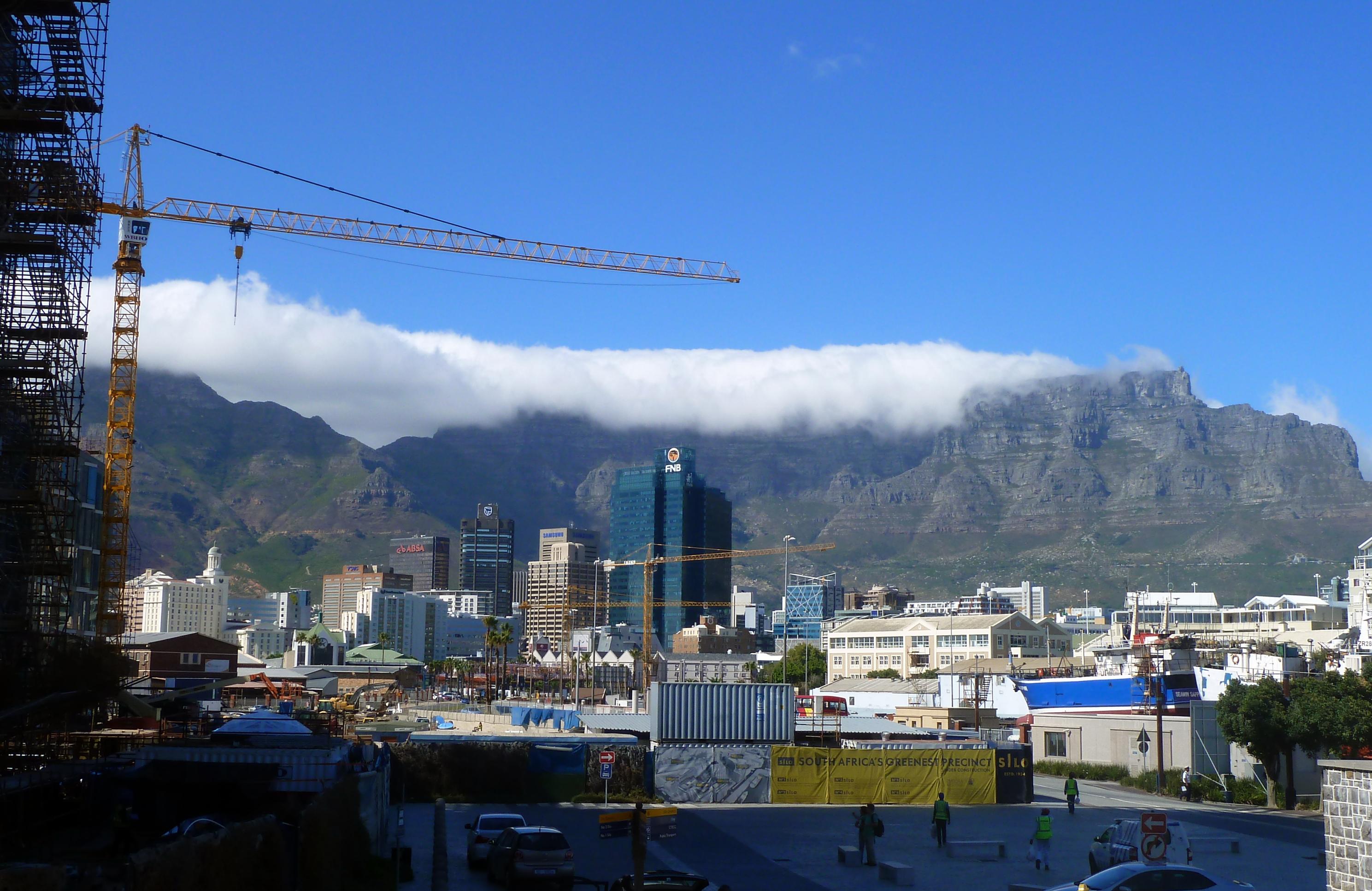Blick auf Kapstadt in Südafrika. Baukräne, Hochhäuser, Gebirge im Hintergrund.