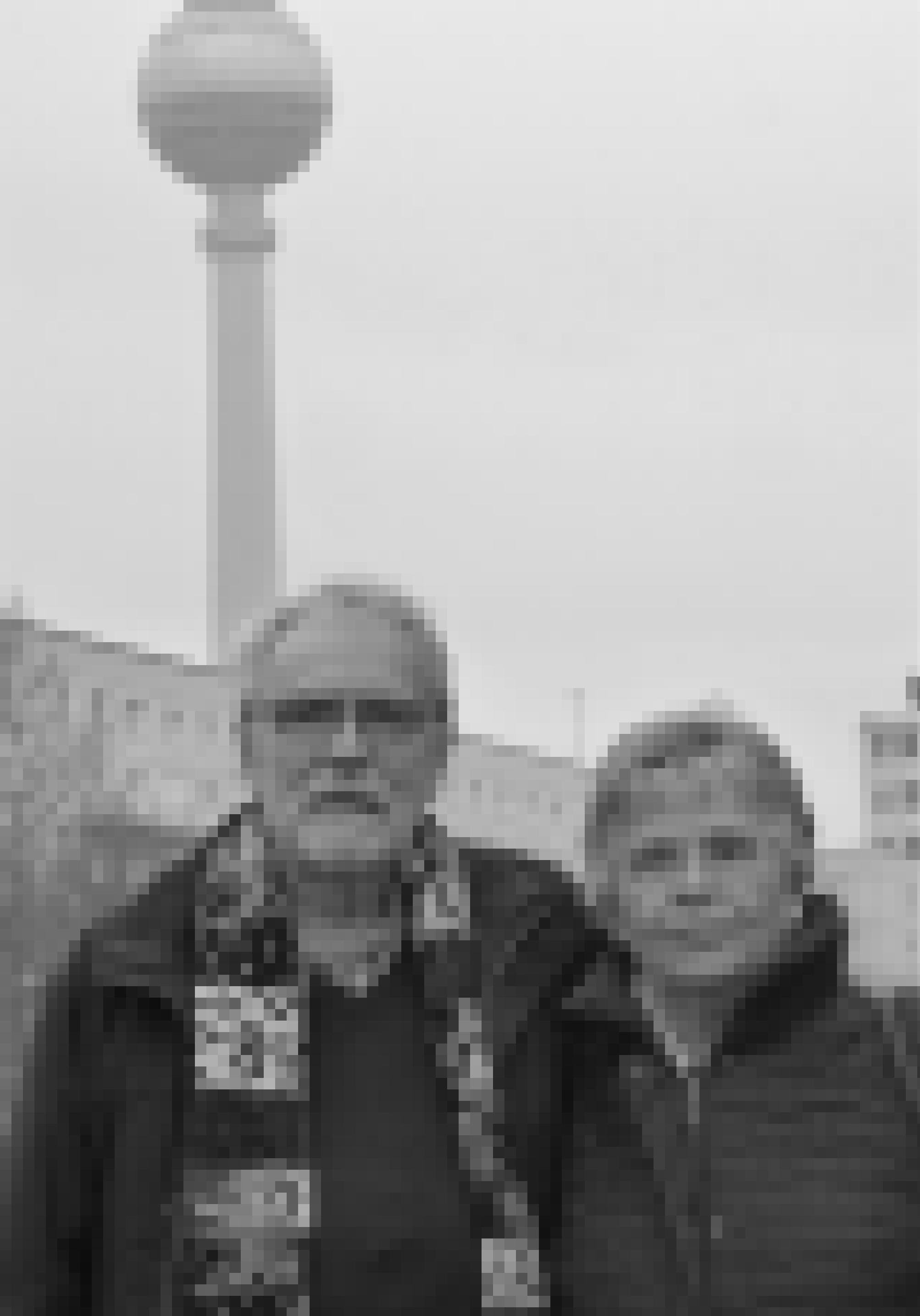 Tatjana Sterneberg und Carl-Wolfgang Holzapfel stehen auf Höhe des Kino International an der Karl-Marx-Allee. Links hinter Holzapfel ist ein Abschnitt des Berliner Fernsehturms zu sehen.