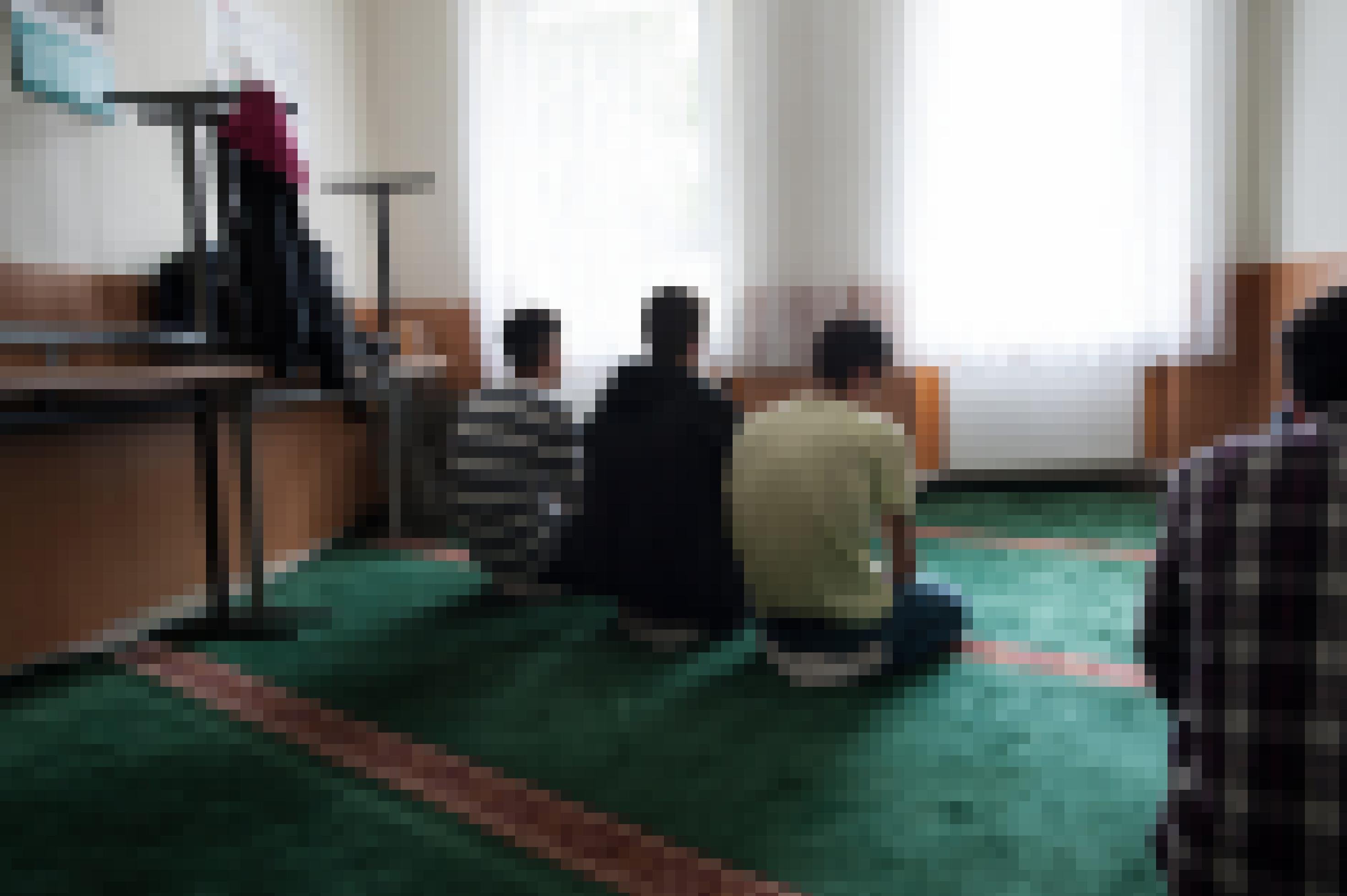 Drei Männer muslimischen Glaubens knien auf einem Teppich und beten.