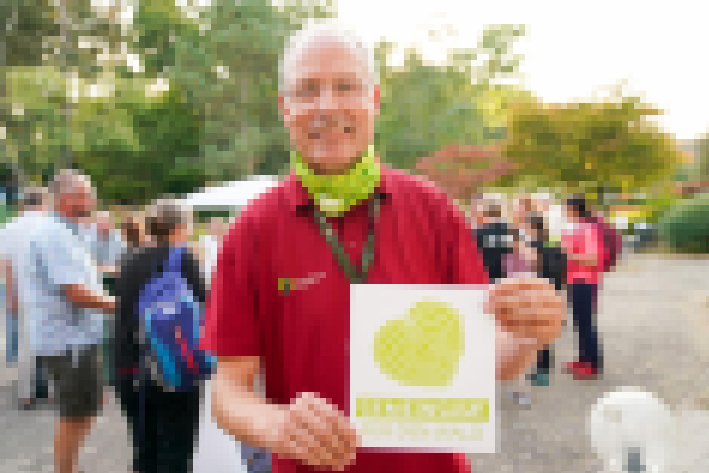 Man hält Blatt Papier mit grünem Herz in die Kamera