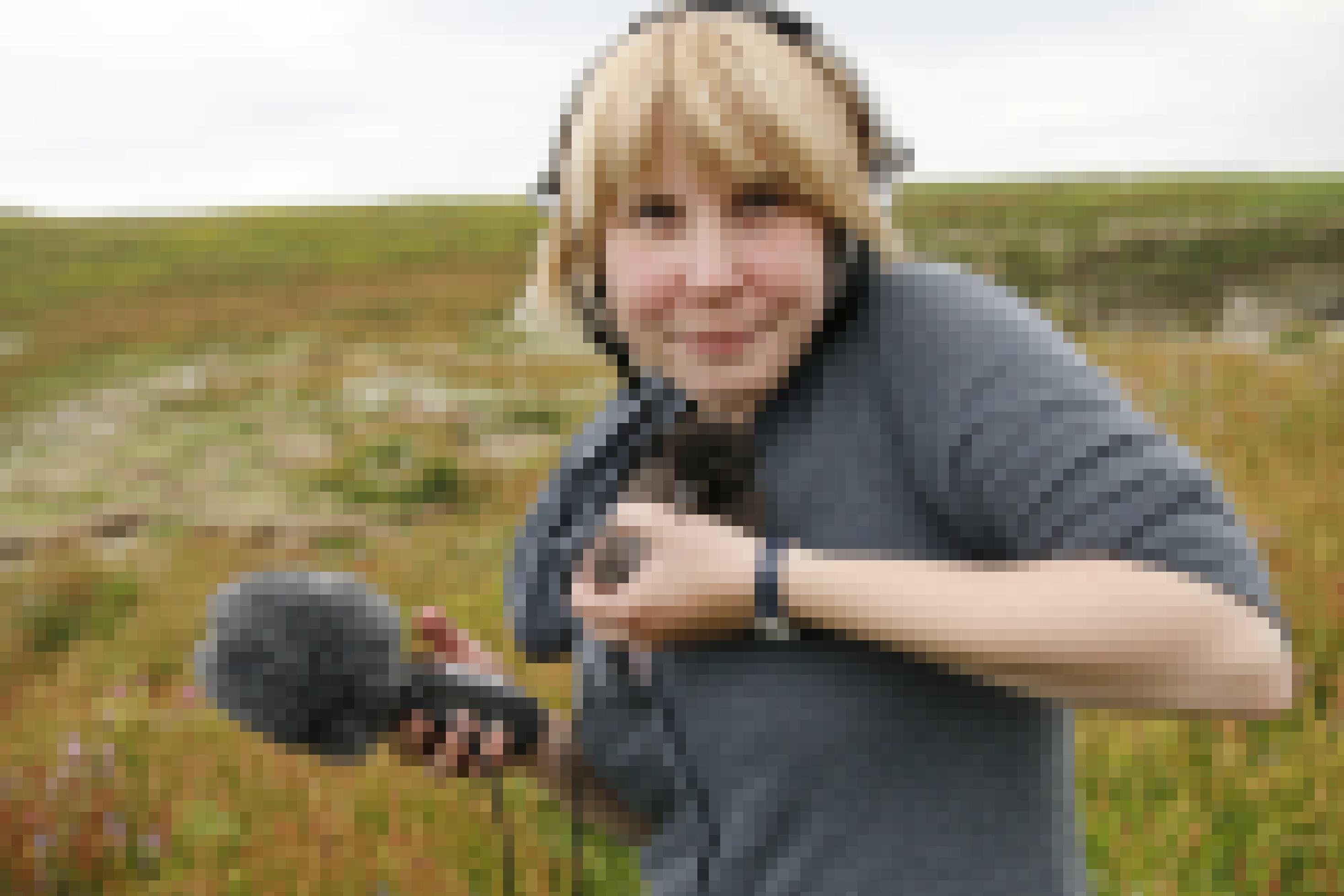 Reporterin Anne Preger mit einem Küken auf dem Arm und einem Mikrophon in der Hand