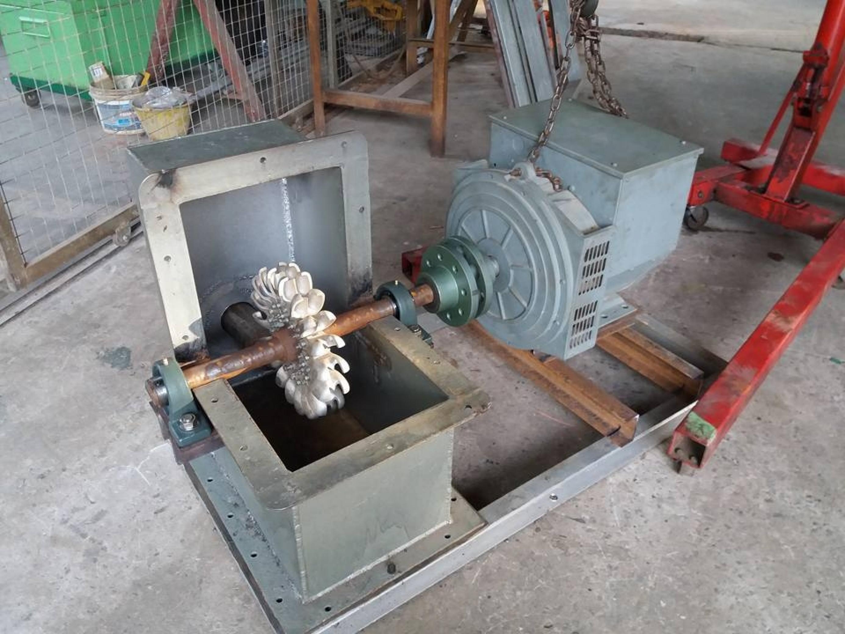 Da Foto zeigt ein Schaufelrad auf der Welle eines Generator in einem noch geöffneten grauen Kasten. – 
… Der Rotor wird dann im Gehäuse installiert und mit einer Stahlwelle mit dem Generator verbunden …
