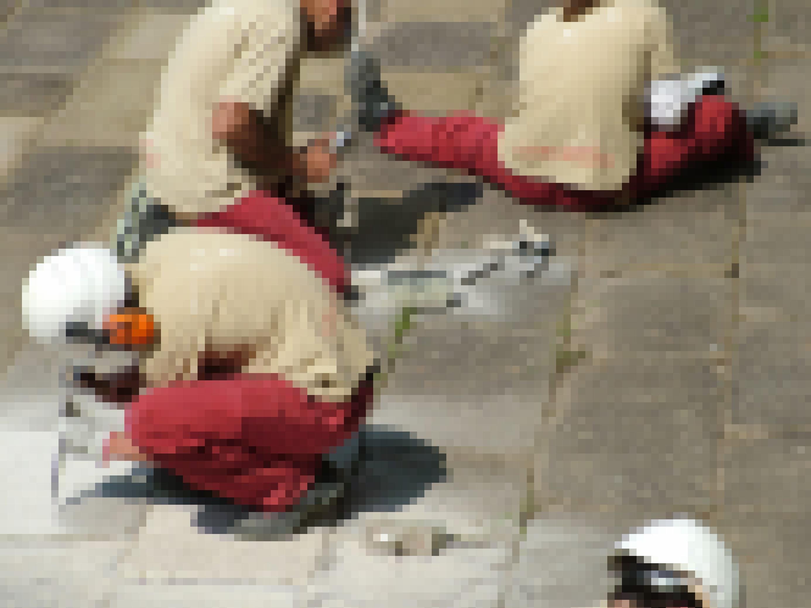 Drei Arbeiter in roten Hosen und cremefarbenen T-shirts und weißen Helmen bearbeiten mit Meißel die Granitplatten und die Fugen dazwischen.