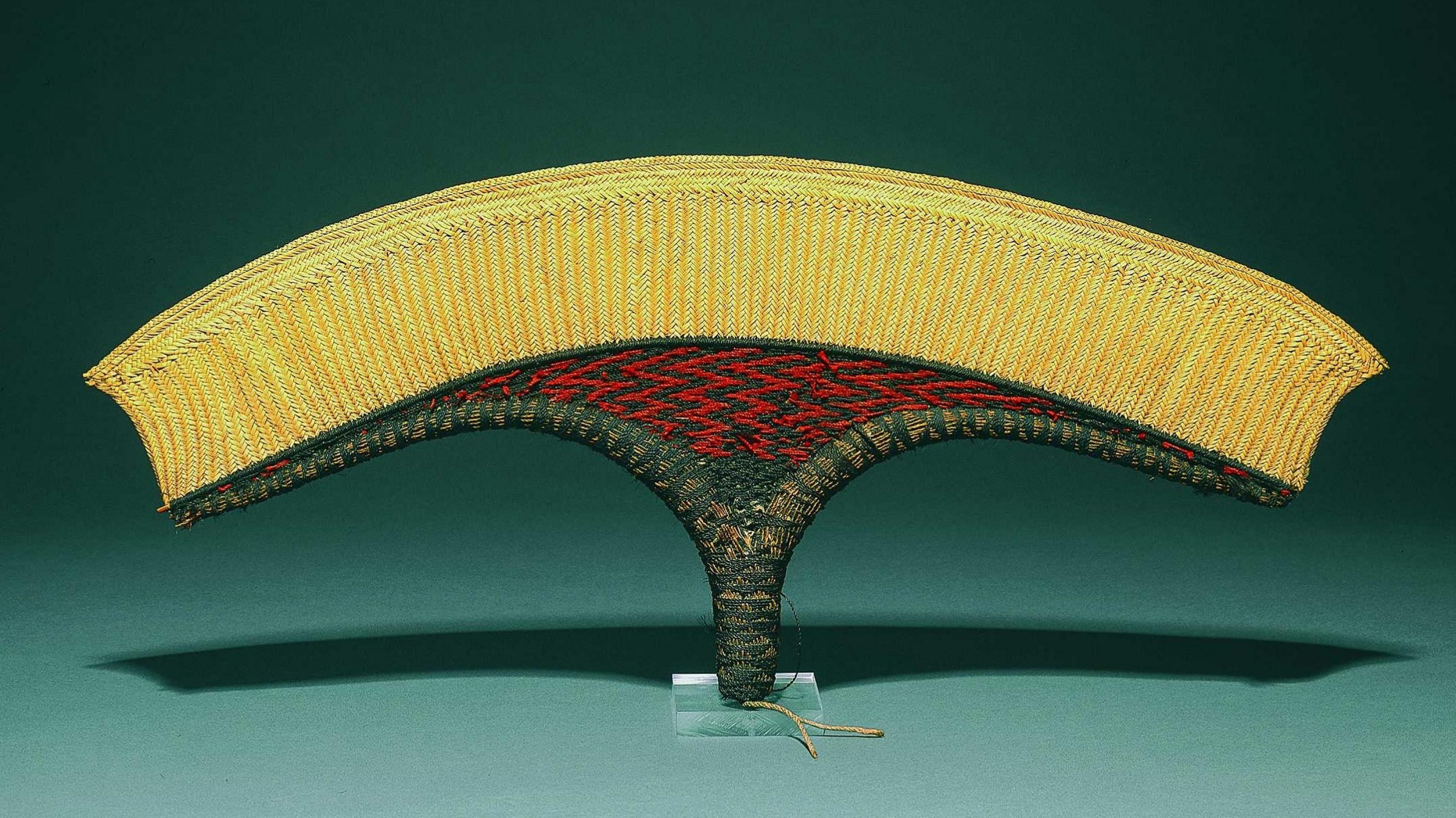Ein aus feinem Kokoshaar kunstvoll geflochtener Fächer in den den Farben Gelb und Rot.