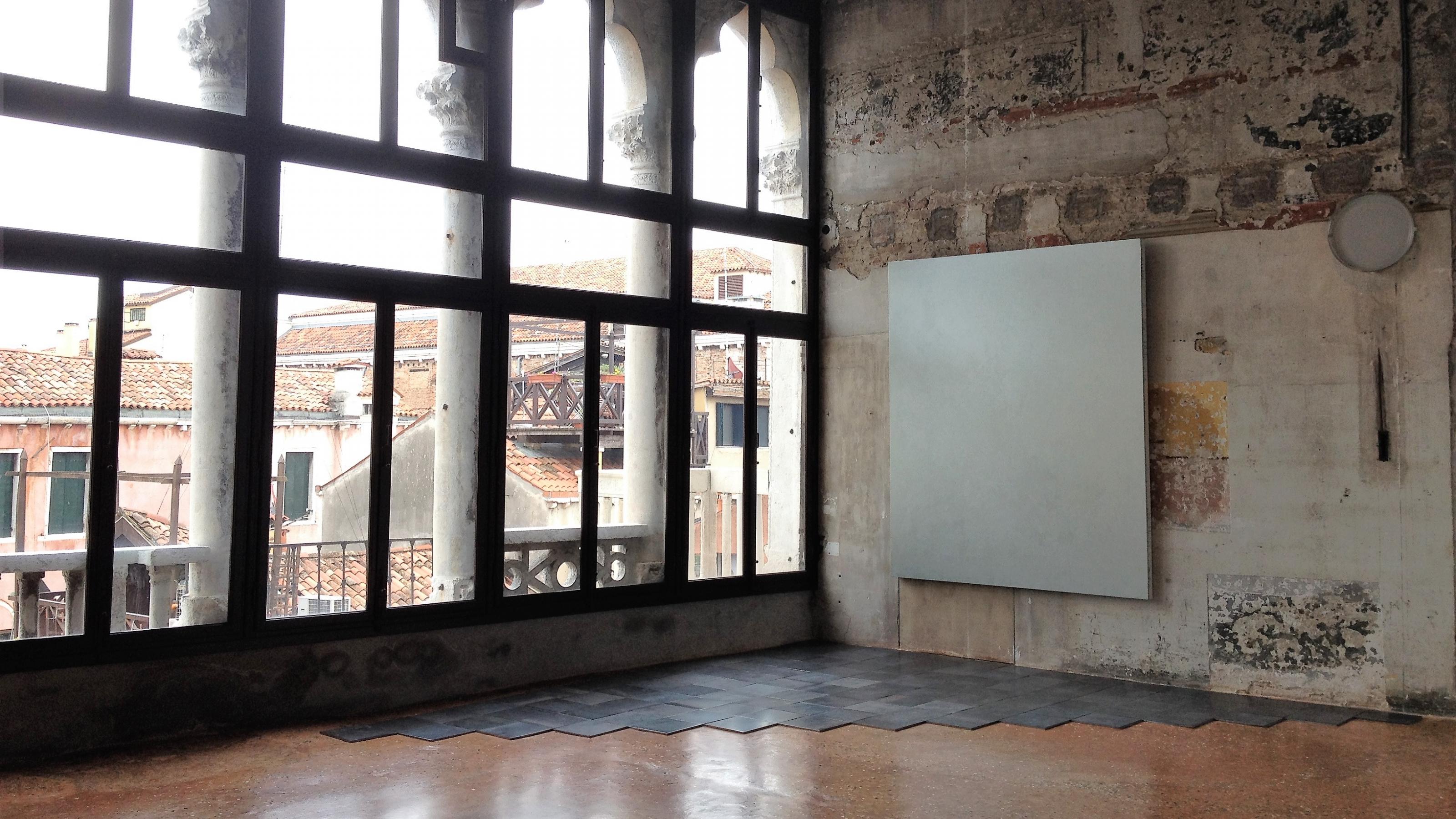 Ein hoher Raum mit einer Fensterfront, in dem Kunstwerke installiert sind.