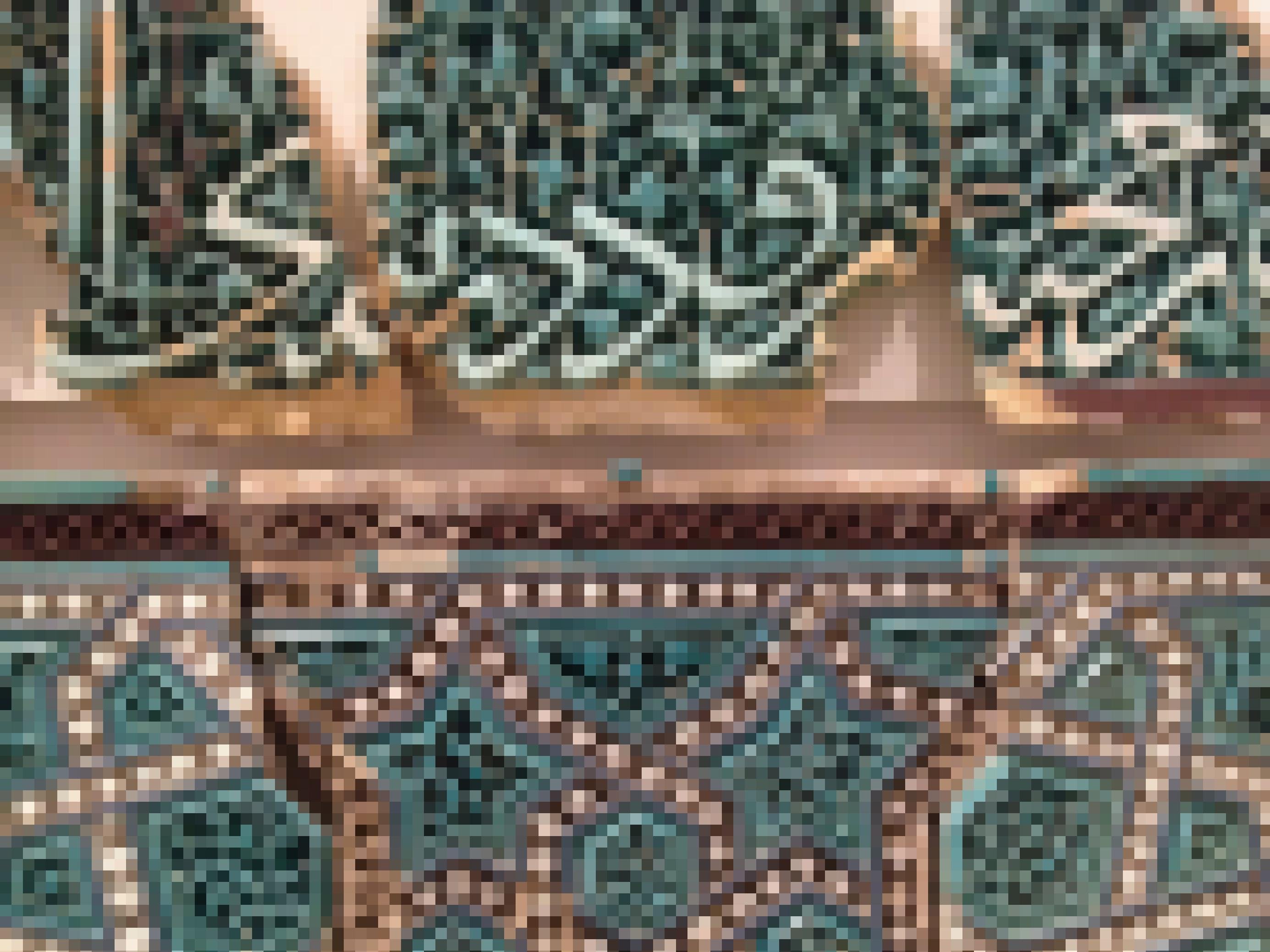 Kunstvoll gestaltete Relief-Kachel mit Ornamenten und arabischem Schriftzug.