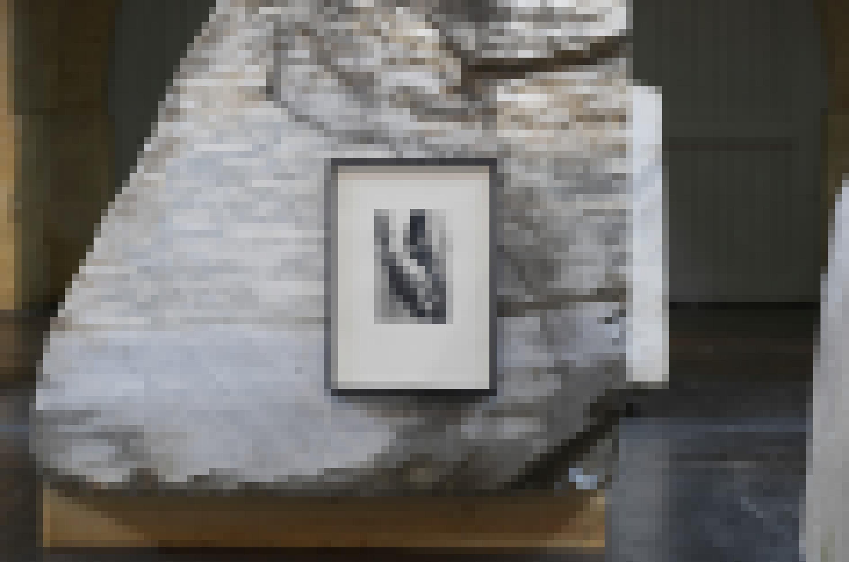 Auf einem ungeformten Marmorblock hängt eine gerahmte Fotografie, die eine Hand einer Skulptur von Michelangelo zeigt.