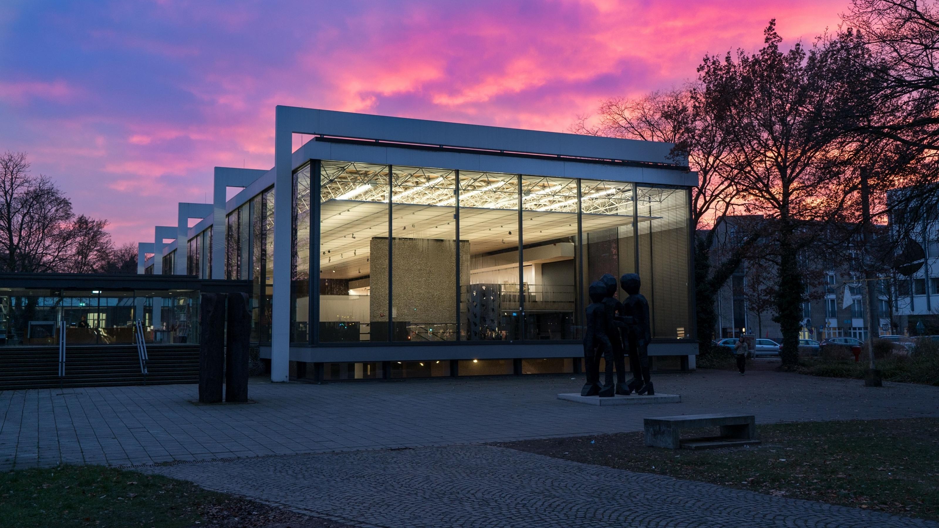 Kubisches Gebäude aus Glas und Stahl bei Abendrot.