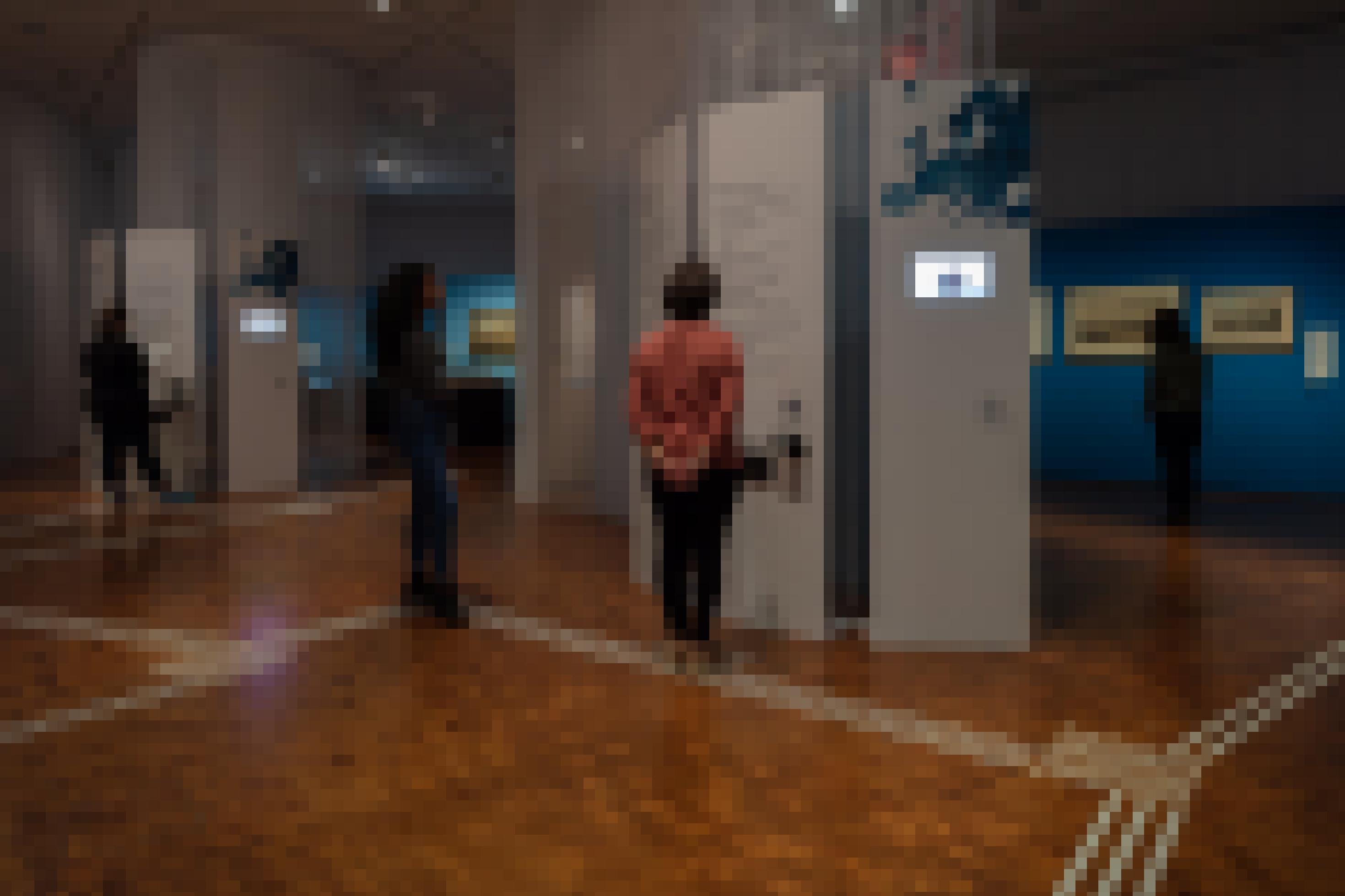 Das Foto zeigt einen Ausstellungsraum mit einer Stellwand. Darauf ist ein Monitor angebracht, über den Inhalte in Gebärdensprache laufen. Auf dem Boden ist ein Leitsystem für sehbehinderte Menschen angebracht.